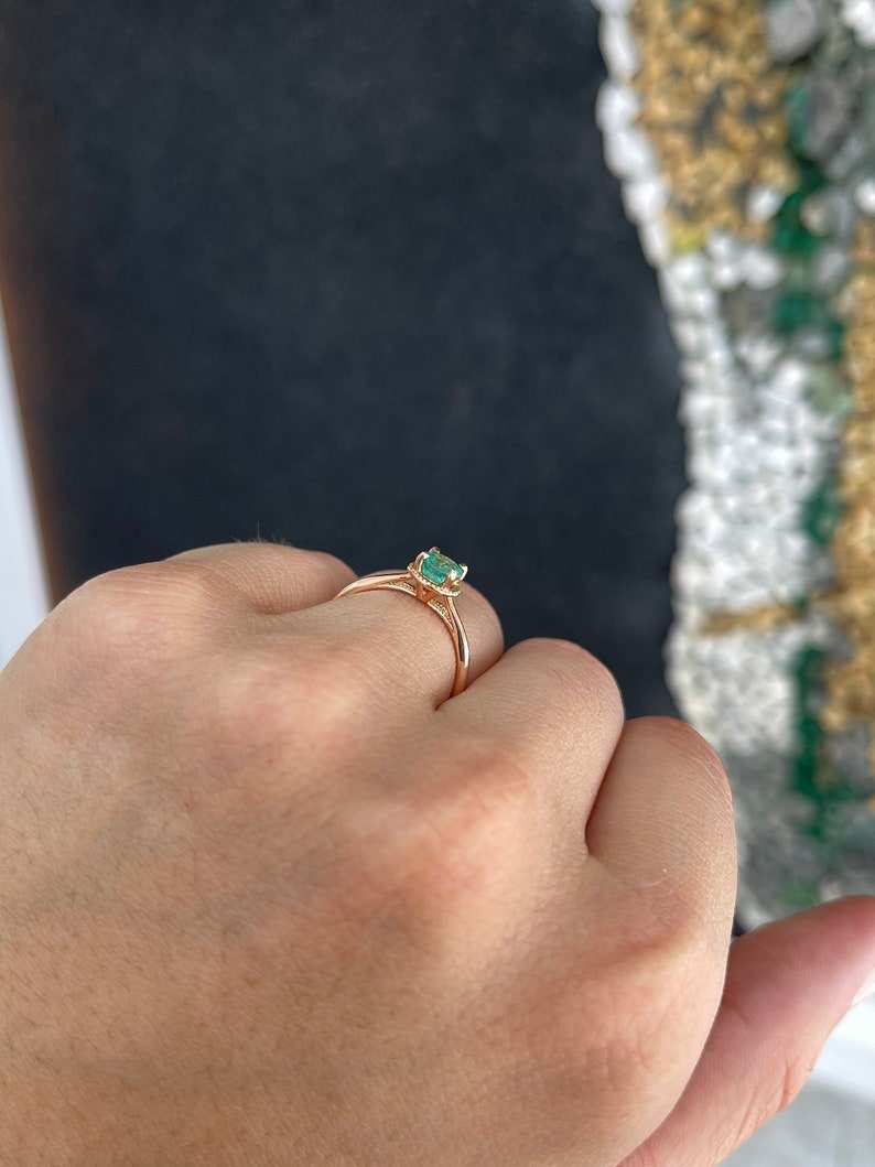 14K rose gold engagement ring with a 0.90ct round cut emerald solitaire on a right hand, featuring a Colombian Emerald brand design