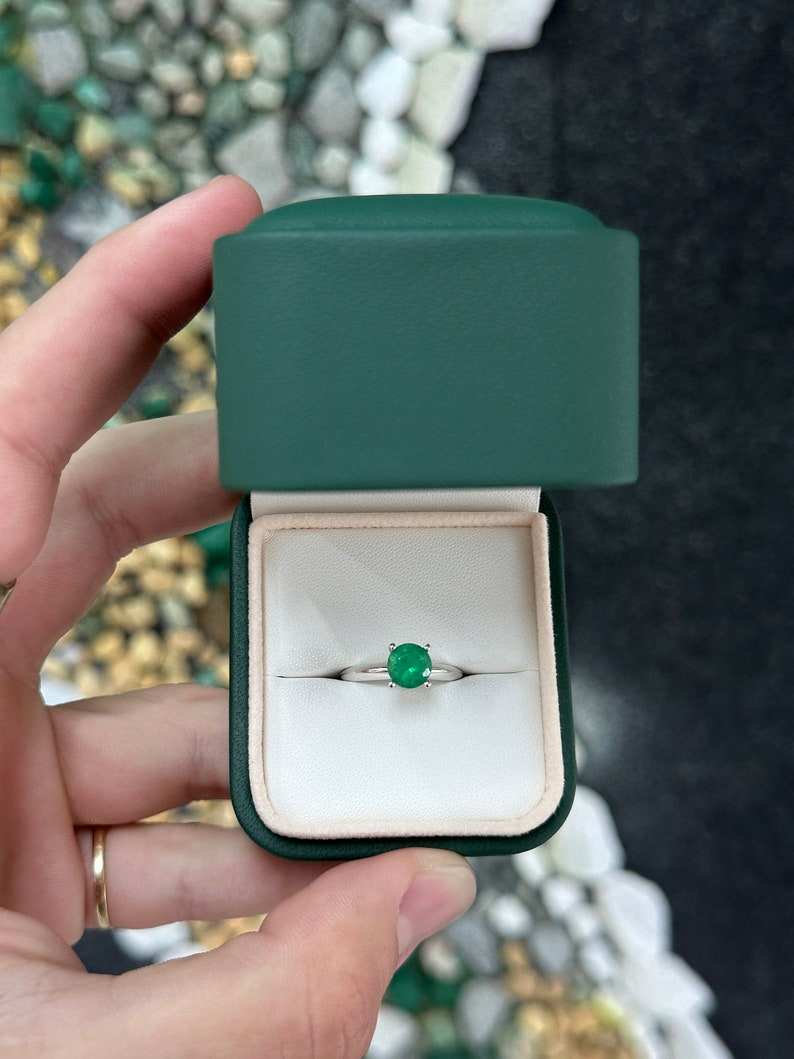 14K white gold engagement ring with a 0.93ct medium dark green round cut emerald in a 4-prong solitaire setting