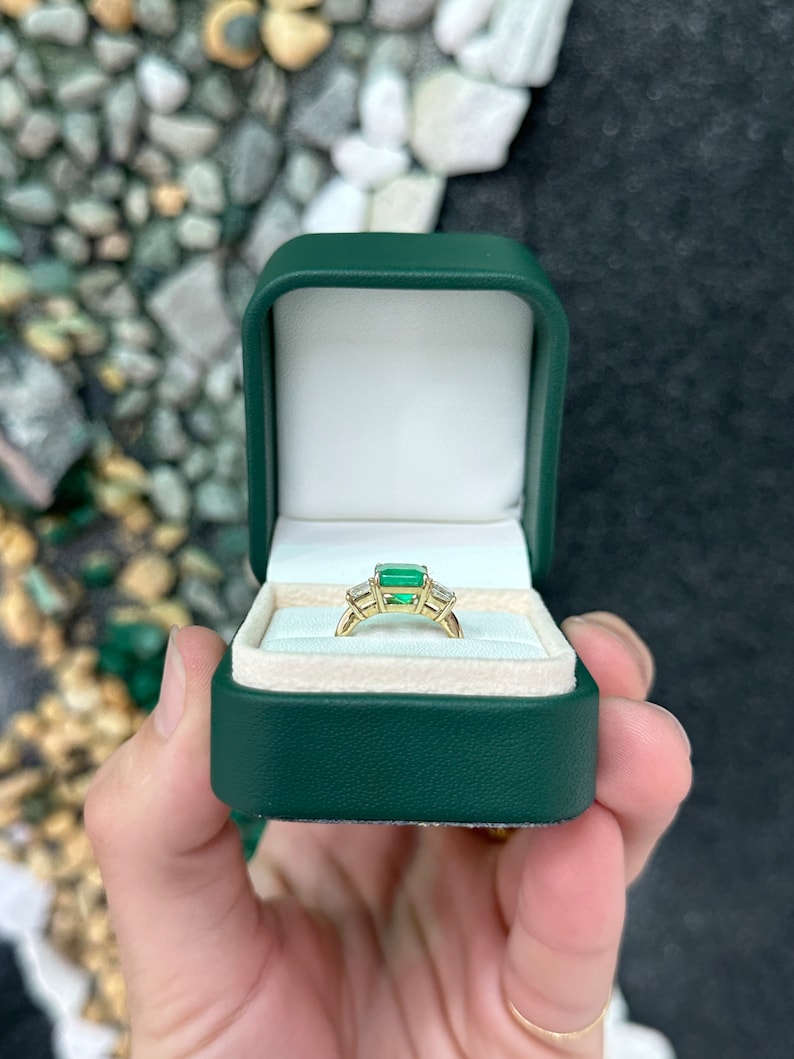Colombian Emerald and diamond 3-stone ring with princess cut diamonds in 14K gold, featuring a vibrant green emerald centerpiece.
