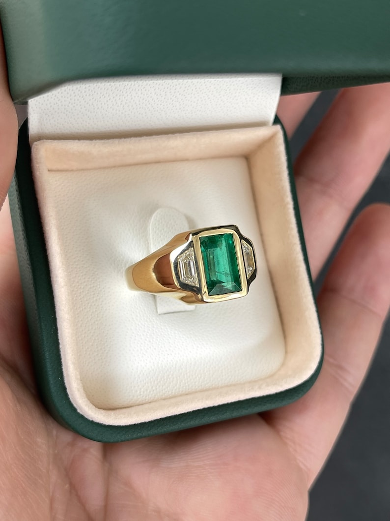Unisex 18K gold ring featuring a 3.30tcw dark green emerald and three Cadillac diamonds, Colombian Emerald brand.