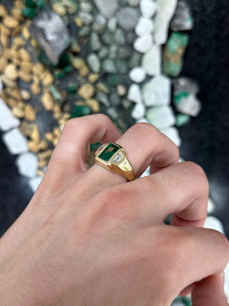 Unisex 18K gold ring with 3.30tcw dark green emerald and three diamond accents, featuring a sleek men's jewelry design.