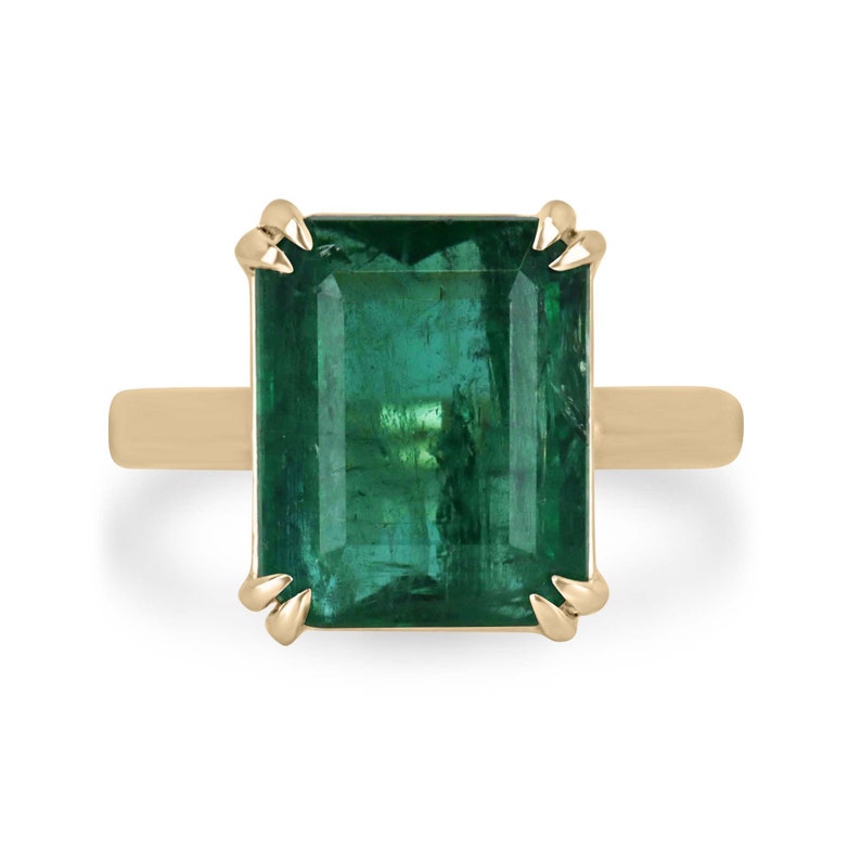 Large 7.90ct Colombian Emerald cut double claw solitaire ring on right hand, crafted in 18K gold.
