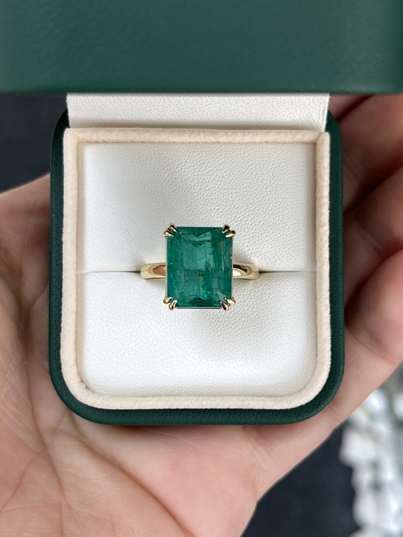 Large 7.90ct emerald cut Colombian Emerald solitaire ring with double claw prongs on a right hand ring style.