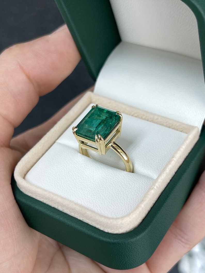 Large 7.90ct emerald cut Colombian Emerald solitaire ring with double claw prongs on a right hand ring finger.