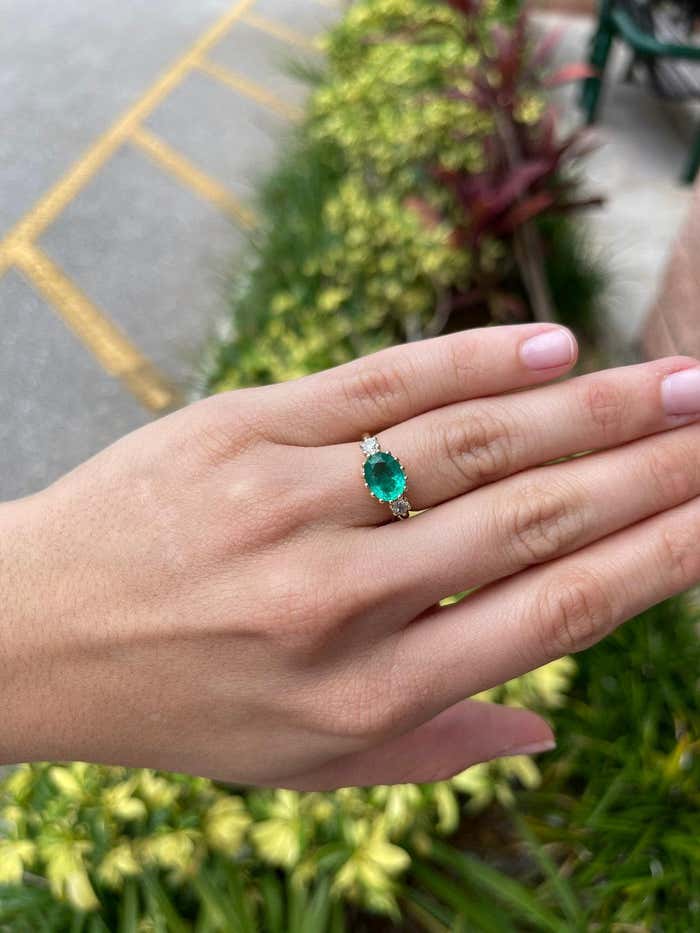 JR Colombian Emeralds 2.60 carat oval emerald and diamond three-stone solitaire ring in 14K gold with green gemstone accents.