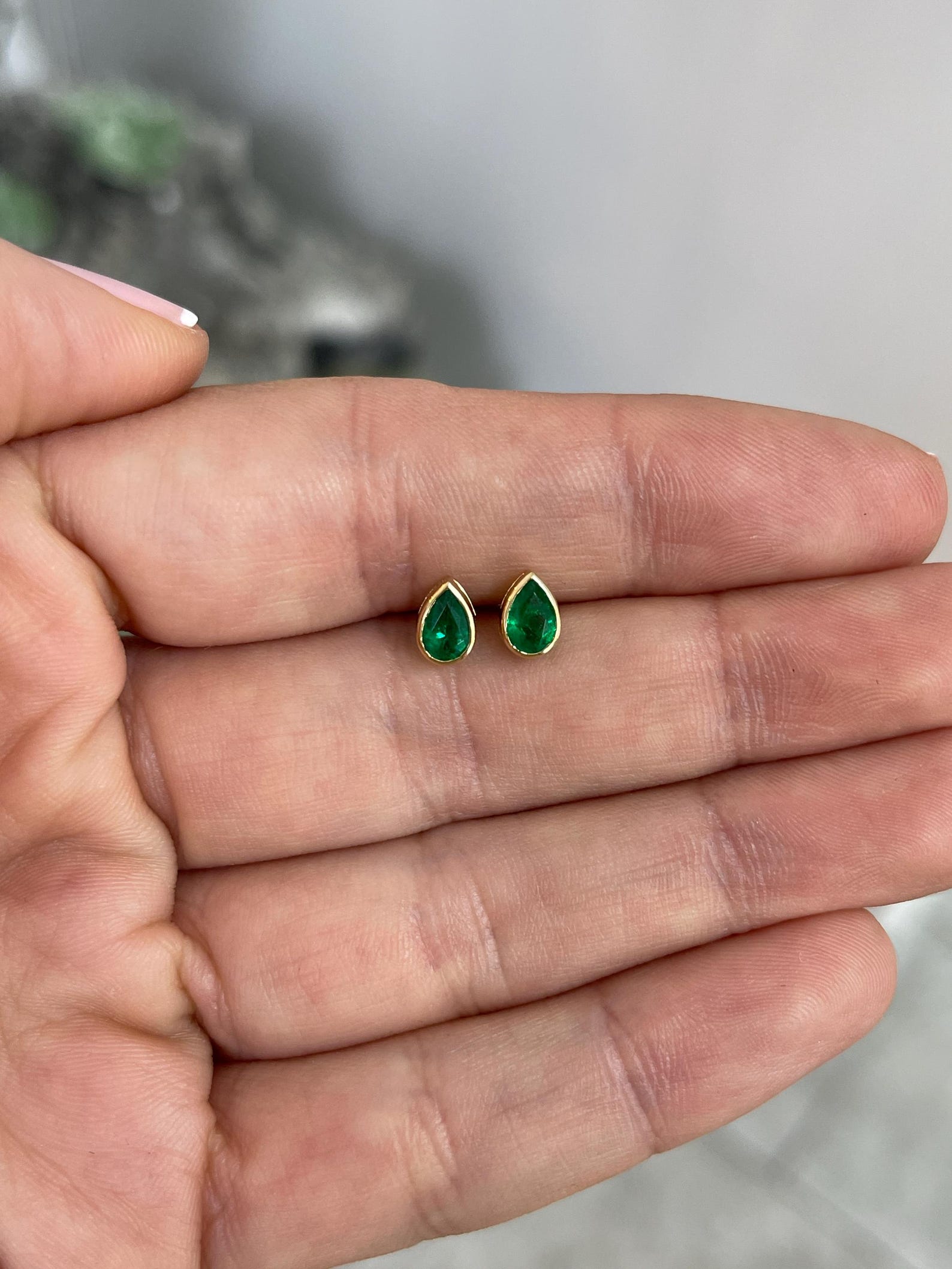 Rich green pear cut Zambian emerald stud earrings with bezel setting by JR Colombian Emeralds, showcasing vibrant gemstone and elegant design.