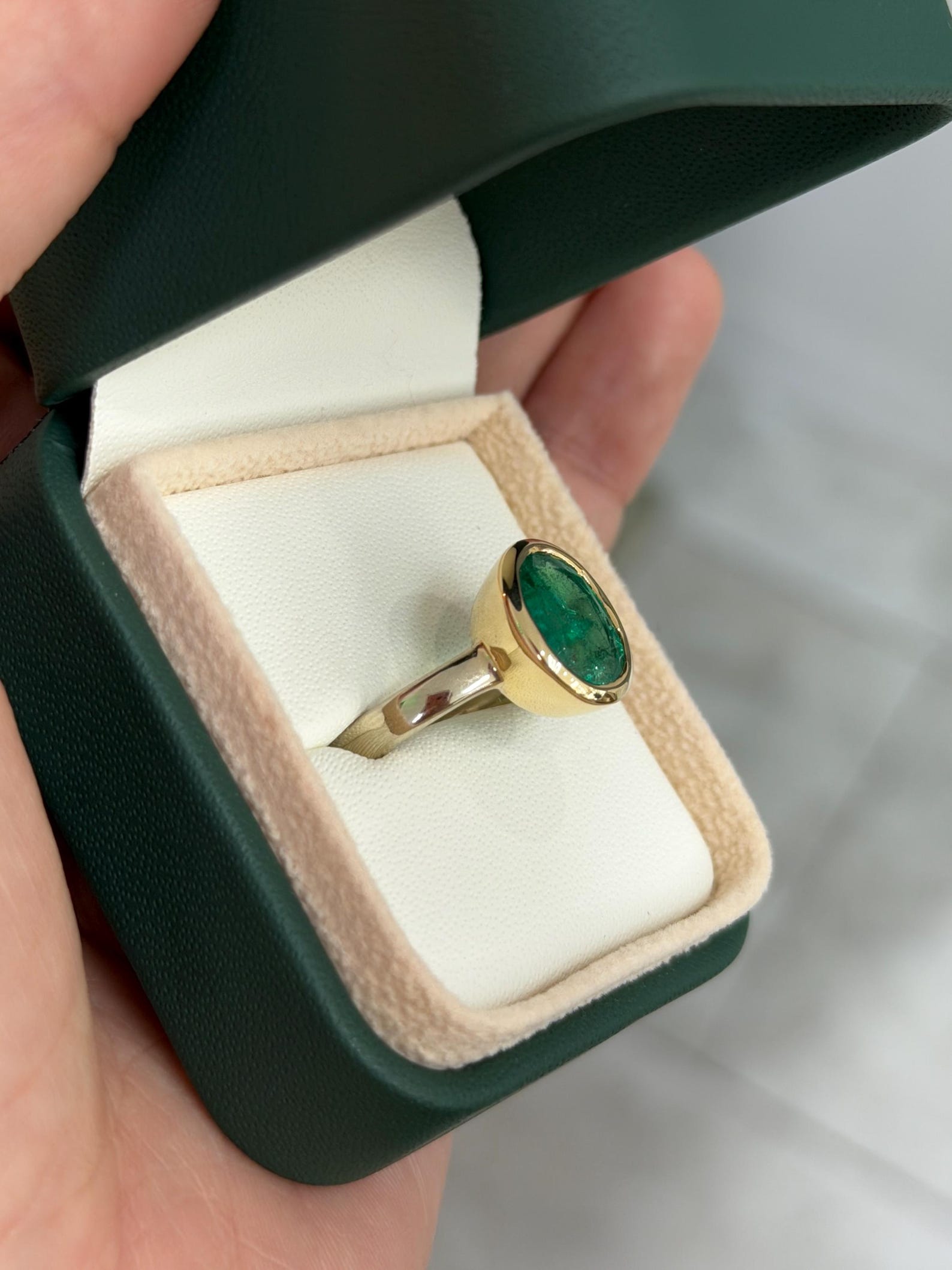 elegant emerald solitaire ring bezel set in two‑toned 14k gold with oval emerald