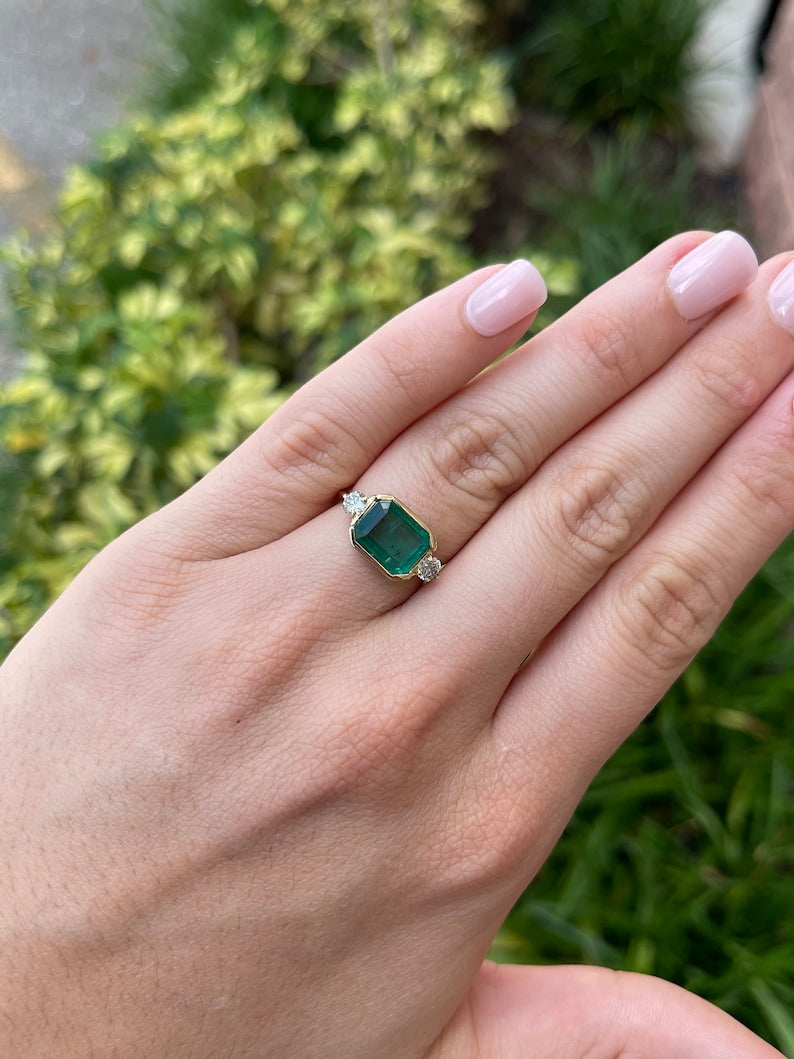 4.35tcw 14K Lush Green Emerald Cut Half Bezel East to West Brilliant Round Cut Diamond 3 Stone Engagement Ring