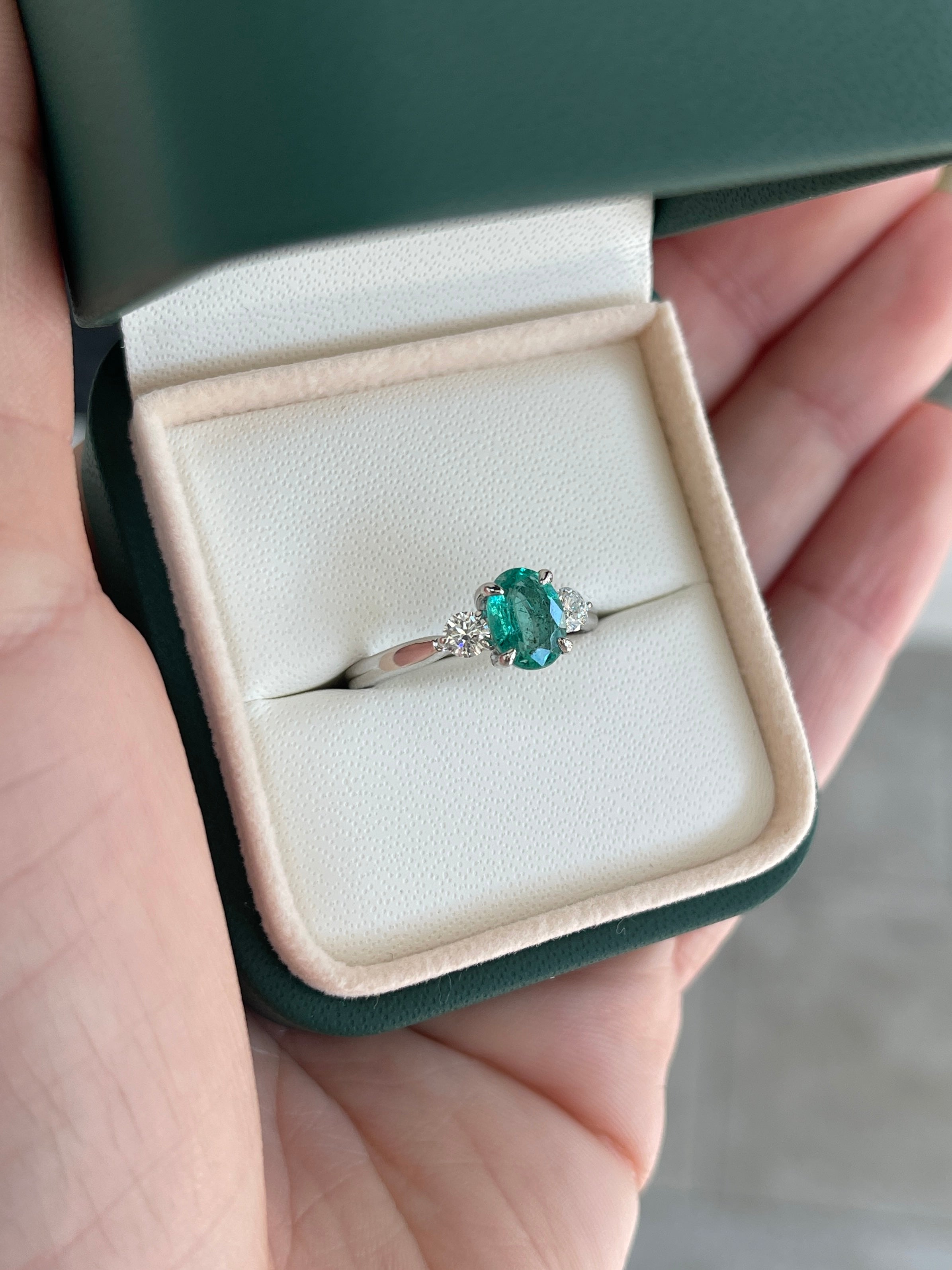 14K gold three-stone ring featuring a bluish-green oval cut emerald and round lab diamonds, crafted by JR Colombian Emeralds.