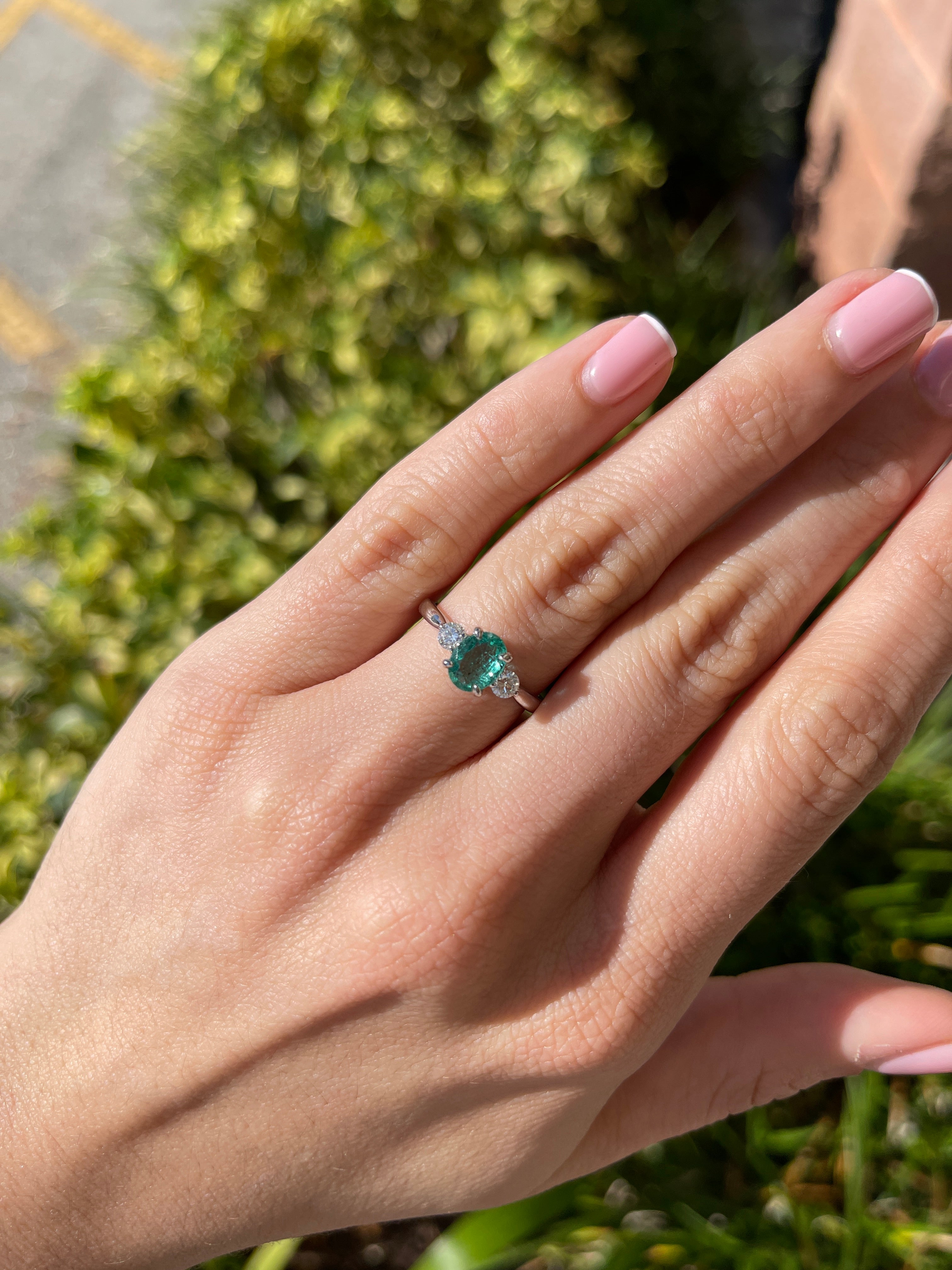 14K gold three-stone ring with 1.50tcw bluish-green oval emerald and round lab diamonds, featuring elegant craftsmanship.