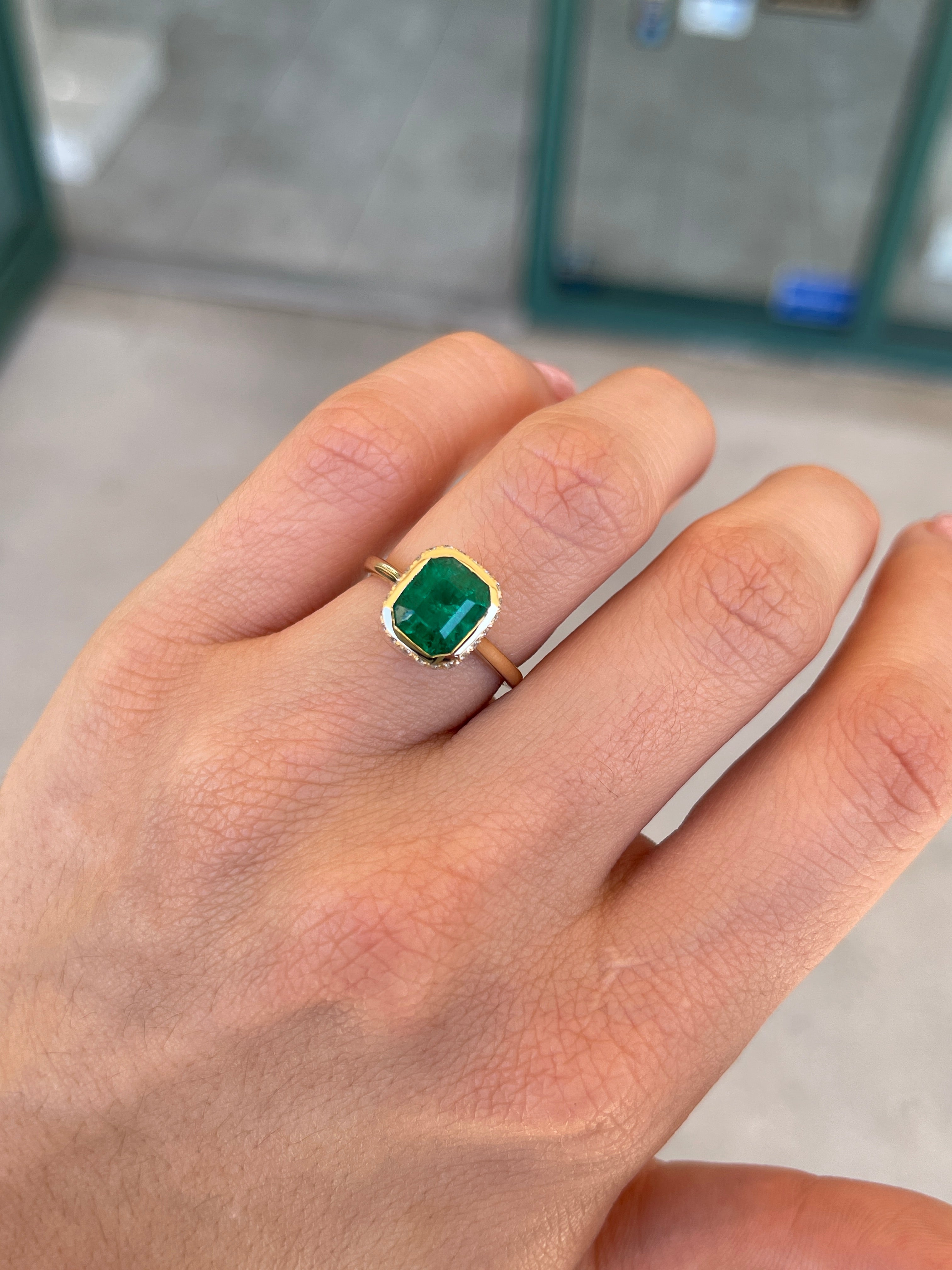 14K Colombian emerald statement ring with bezel setting, diamond pave hidden halo, showcasing vibrant green emeralds and sparkling accents.