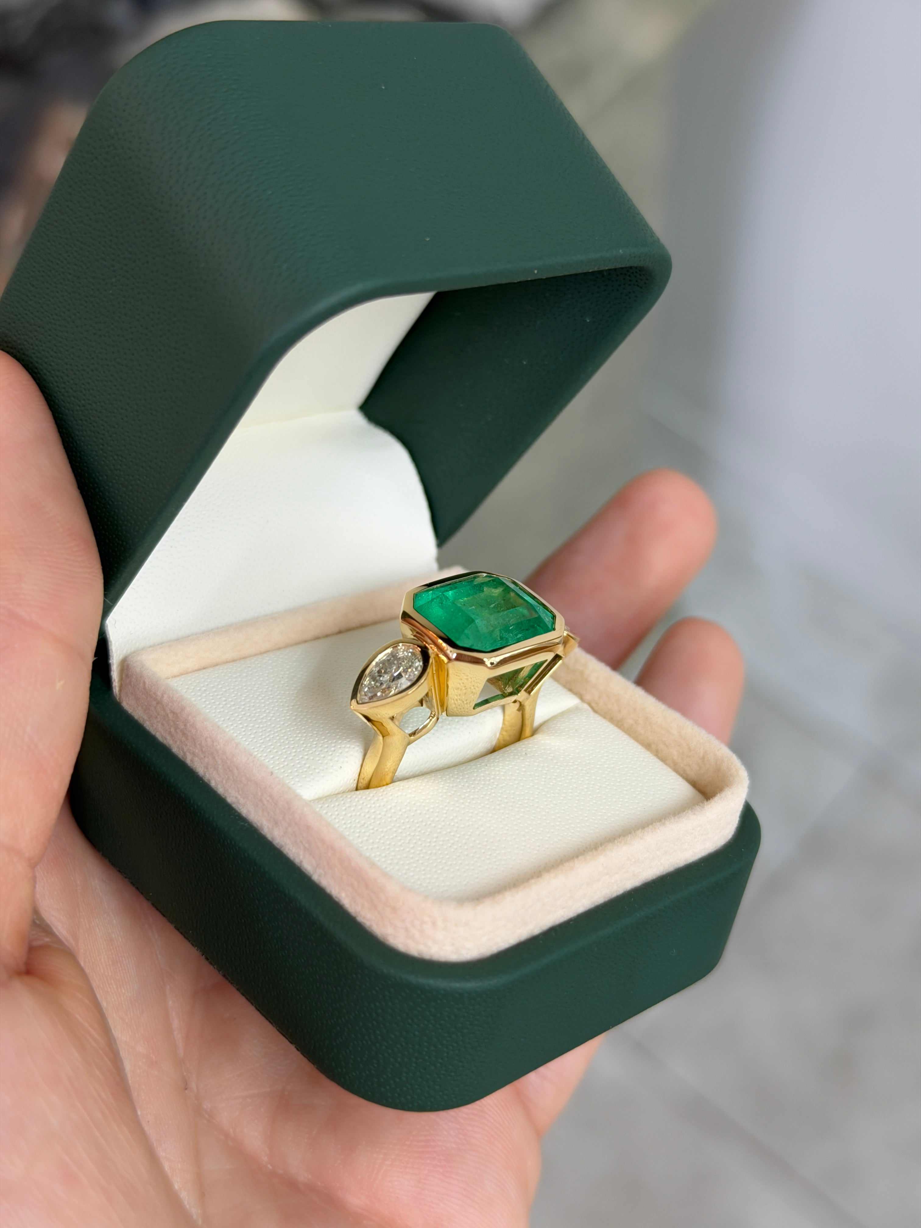 East to West Colombian Emerald and pear diamond three-stone ring in 18K gold, featuring 10.93tcw of gemstones and intricate design.
