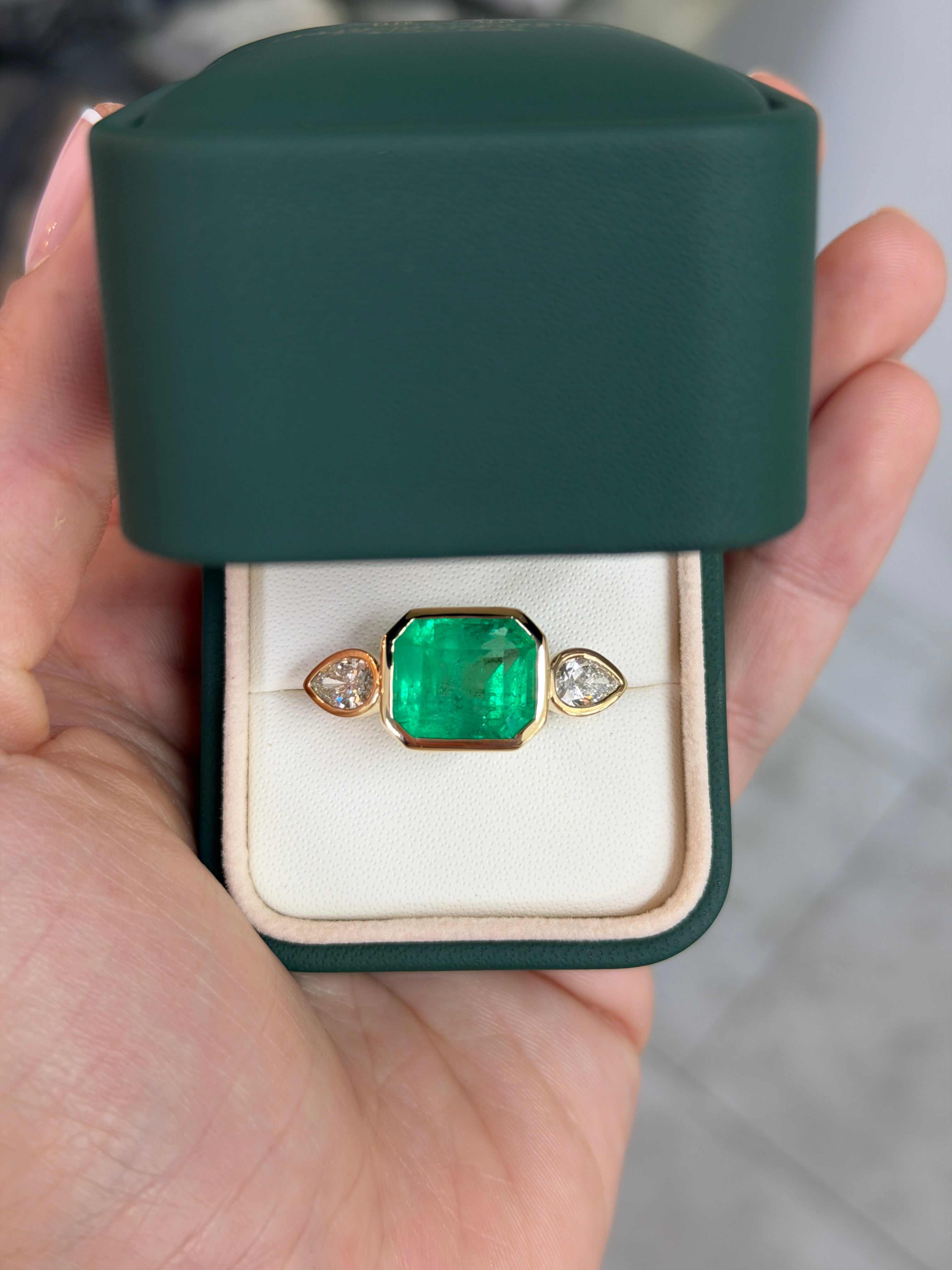 East to West Colombian Emerald and pear-shaped diamond three-stone ring in 18K gold by JR Colombian Emeralds.