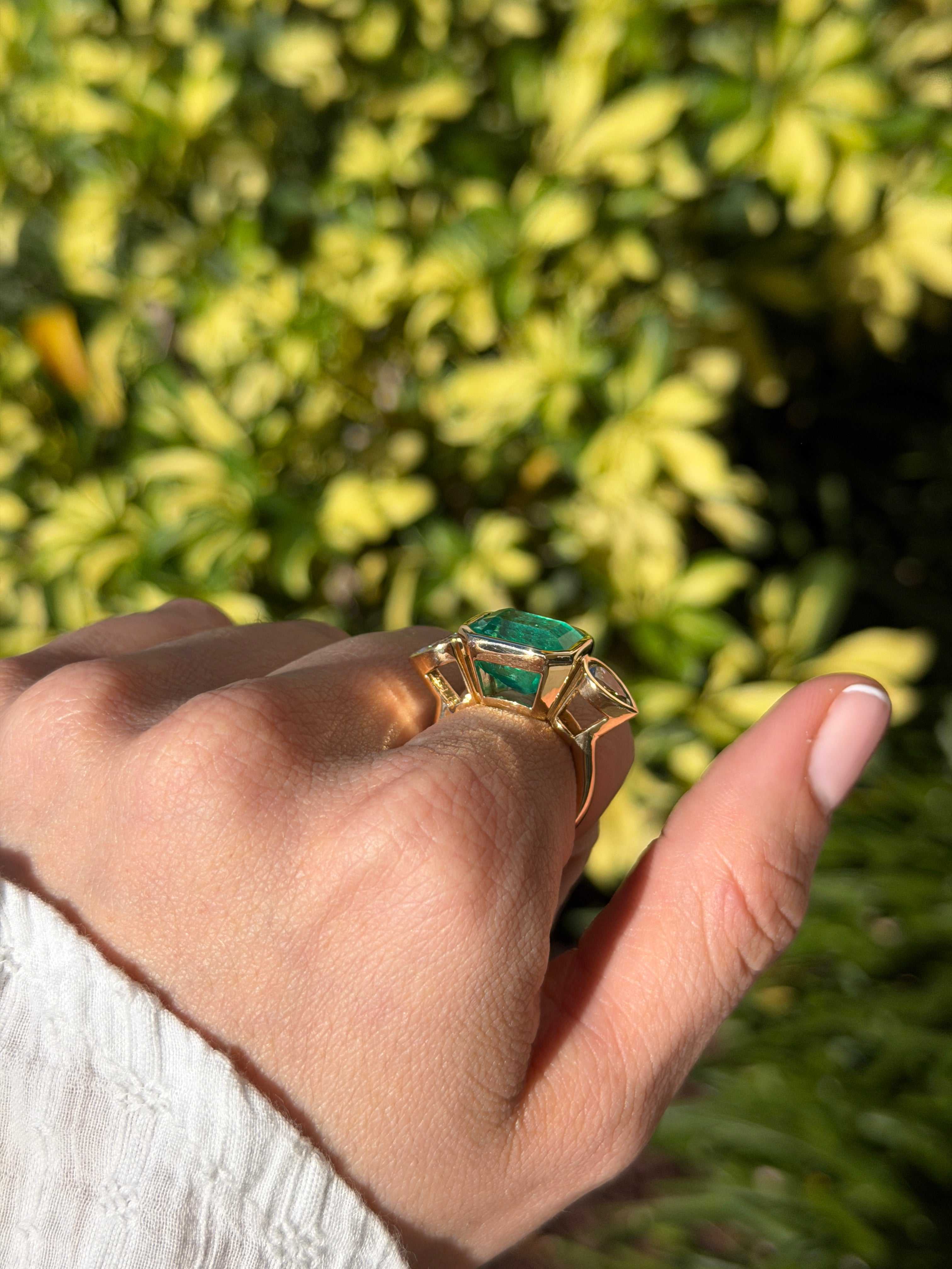 East to West Colombian emerald and pear diamond three-stone ring in 18K gold, featuring vibrant green emeralds and sparkling diamonds.