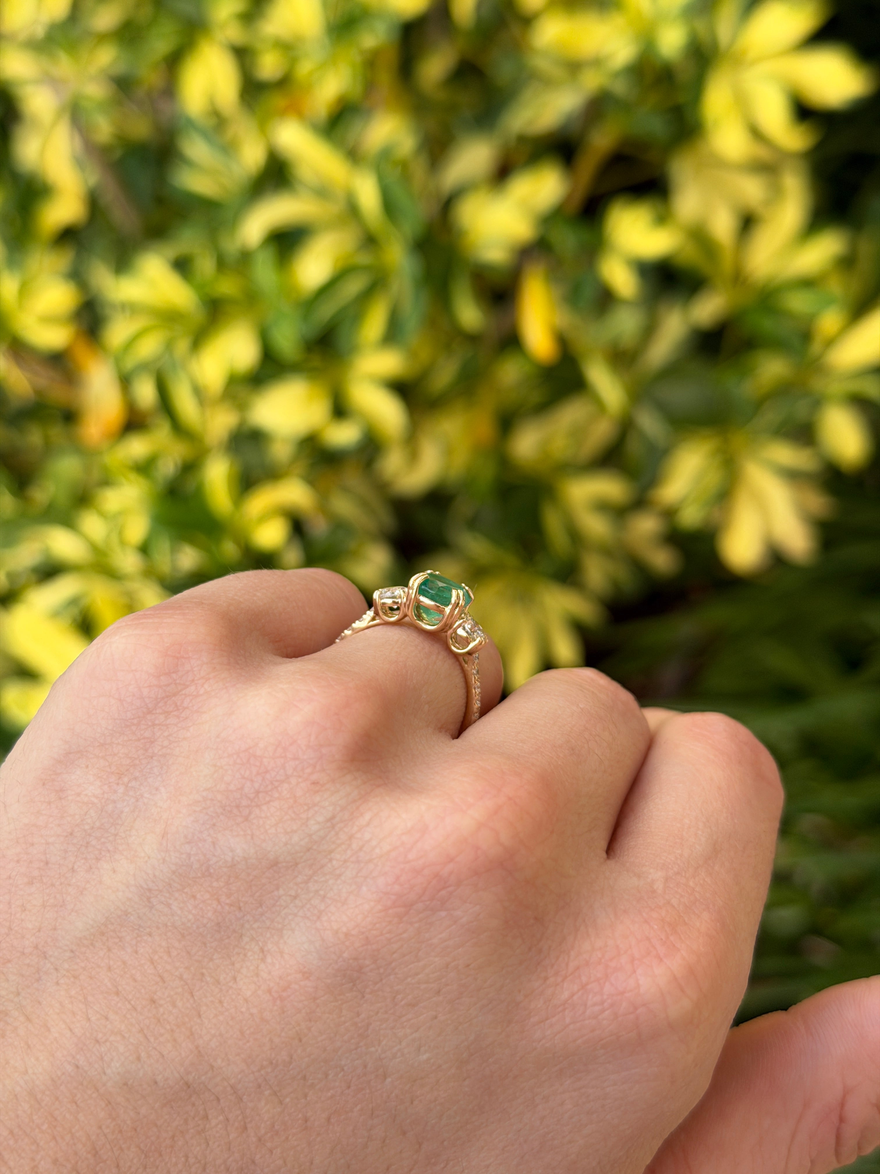 14K gold engagement ring featuring 2.60tcw natural round emerald and lab diamond three-stone design with accent stones.