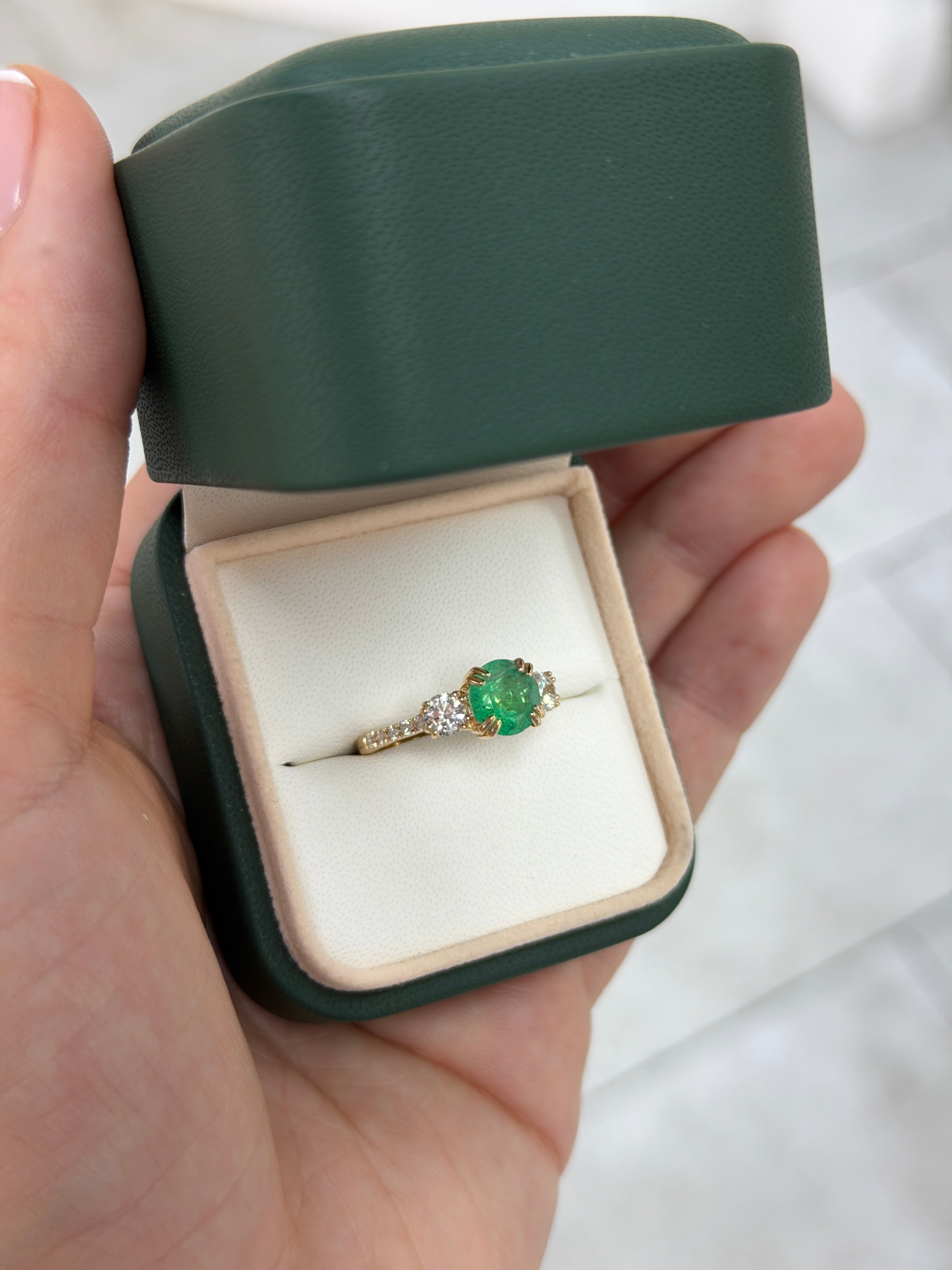14K gold engagement ring with three round emeralds and lab diamonds, featuring accent stones and a detailed band design.