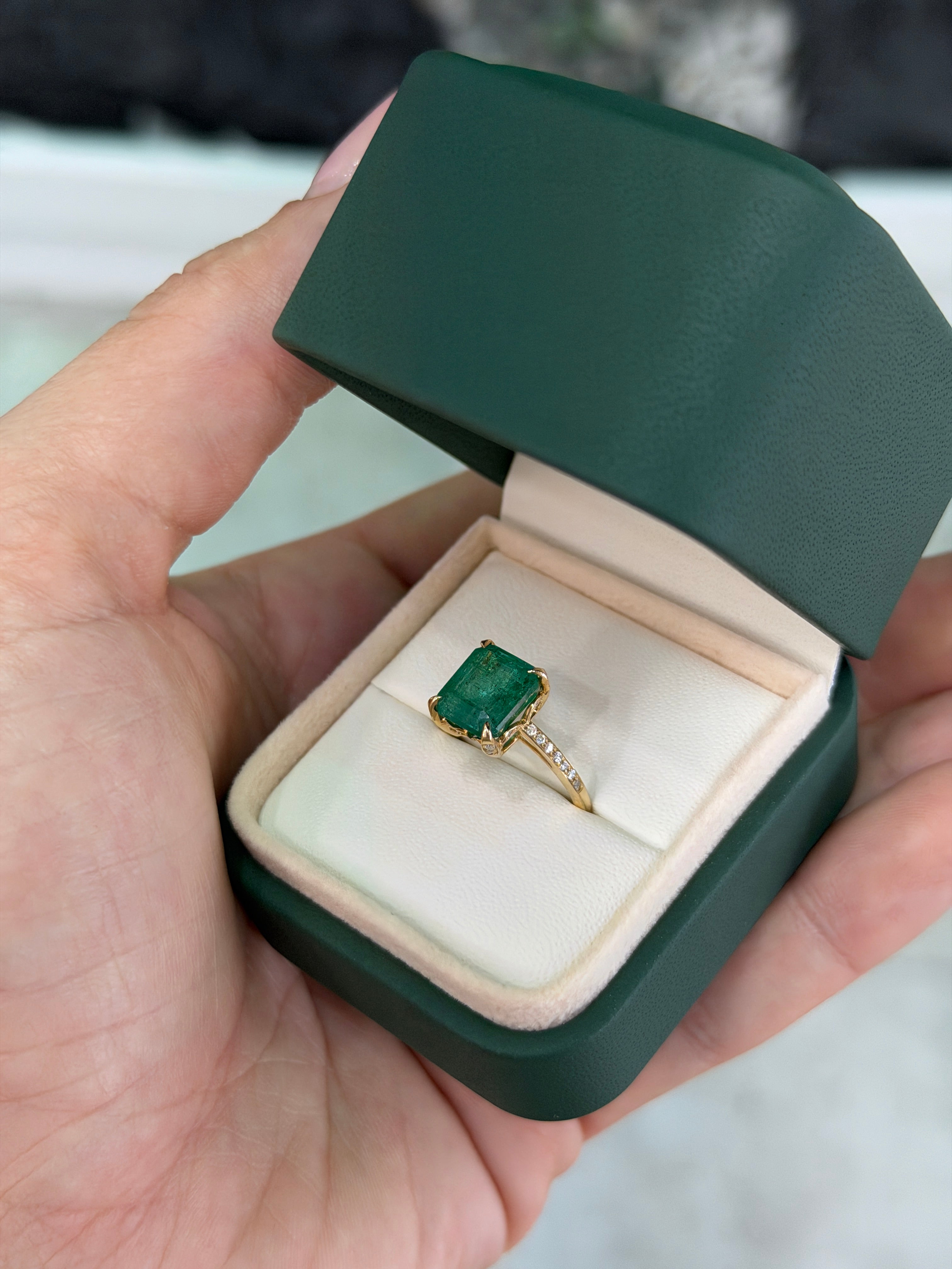 14K gold engagement ring with a 3.50tcw natural emerald center stone, surrounded by a diamond halo and detailed shank.