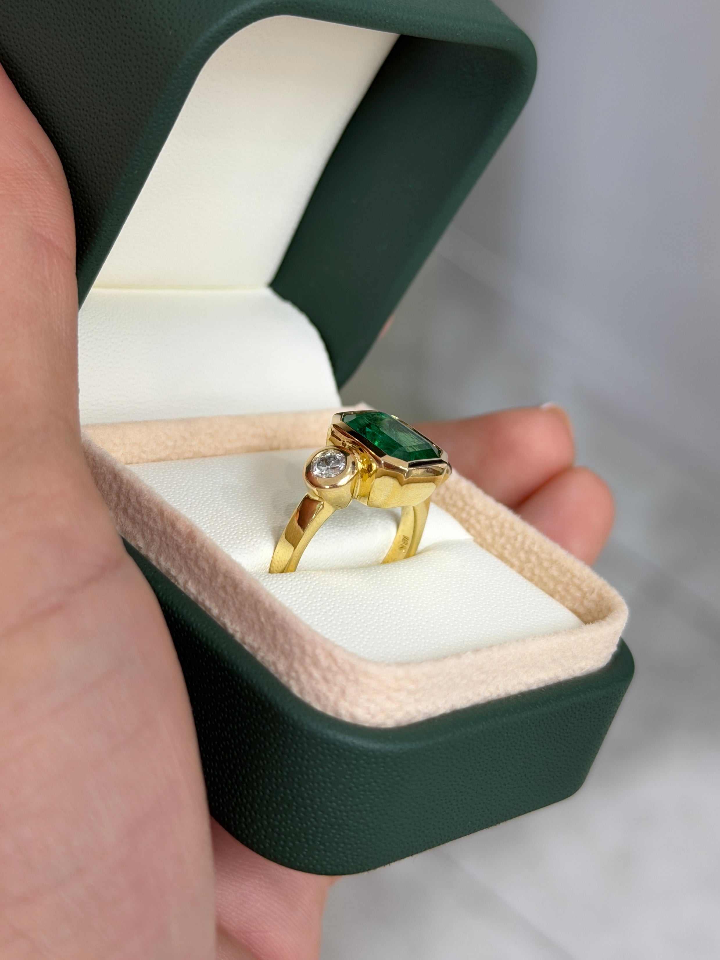 Natural dark emerald and round diamond three-stone ring in 18K gold by JR Colombian Emeralds, showcasing a luxurious jewelry design.