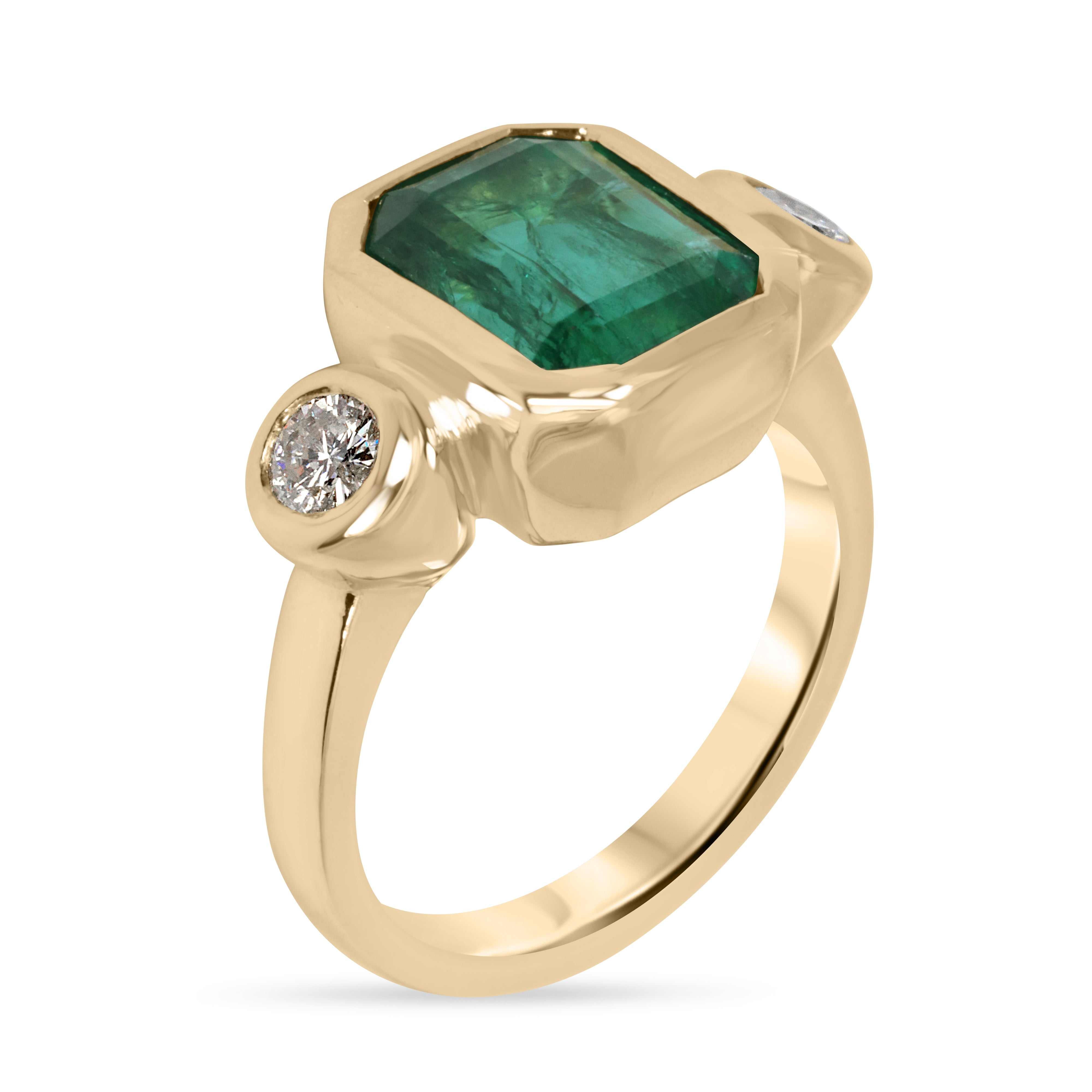 Natural dark emerald and round diamond three-stone ring in 18K gold, featuring the JR Colombian Emeralds brand on a jewelry display.