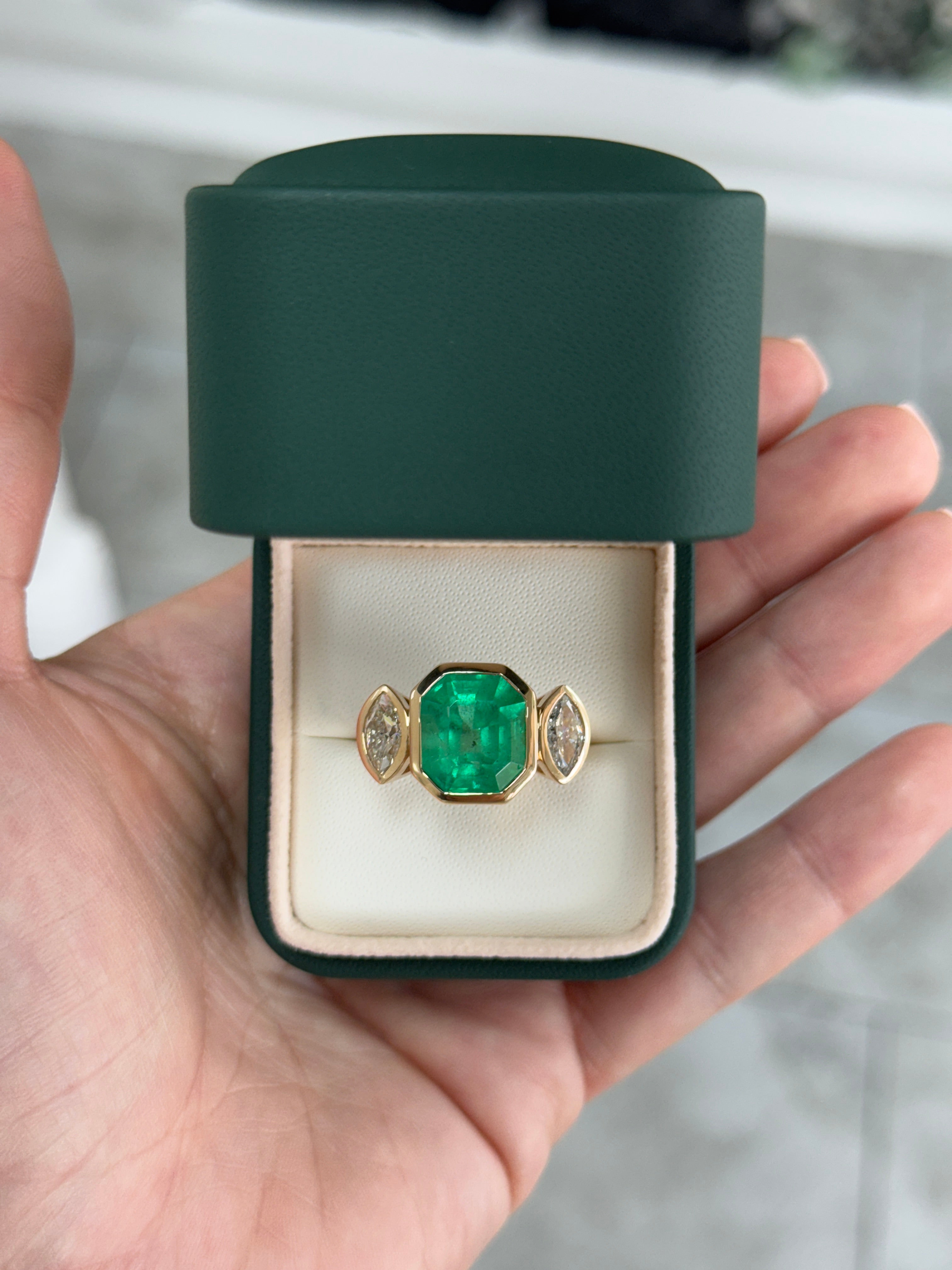 Emerald cut Colombian emerald and marquise diamond trilogy ring in 18K gold, showcasing a stunning jewelry design.