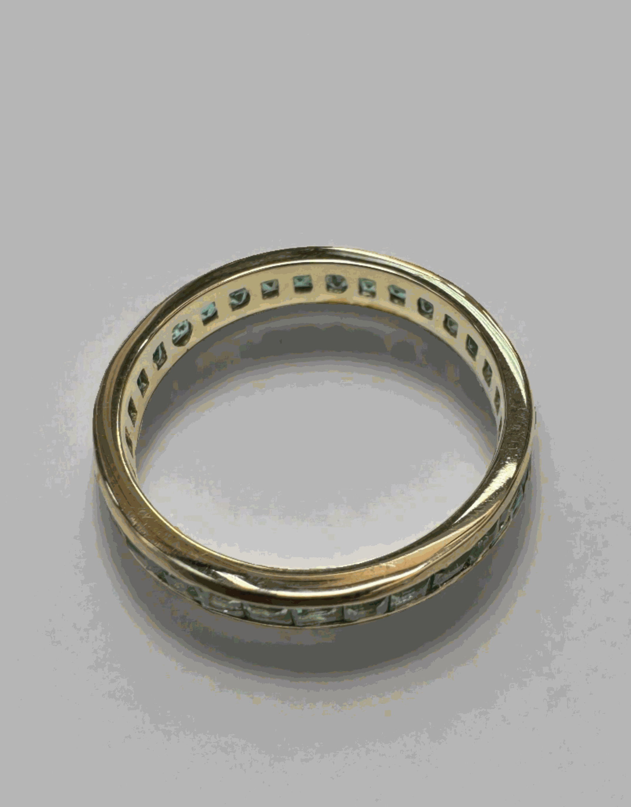 14K gold eternity band with princess-cut emeralds and channel setting, featuring 1.44 carats of sparkling Colombian emeralds.