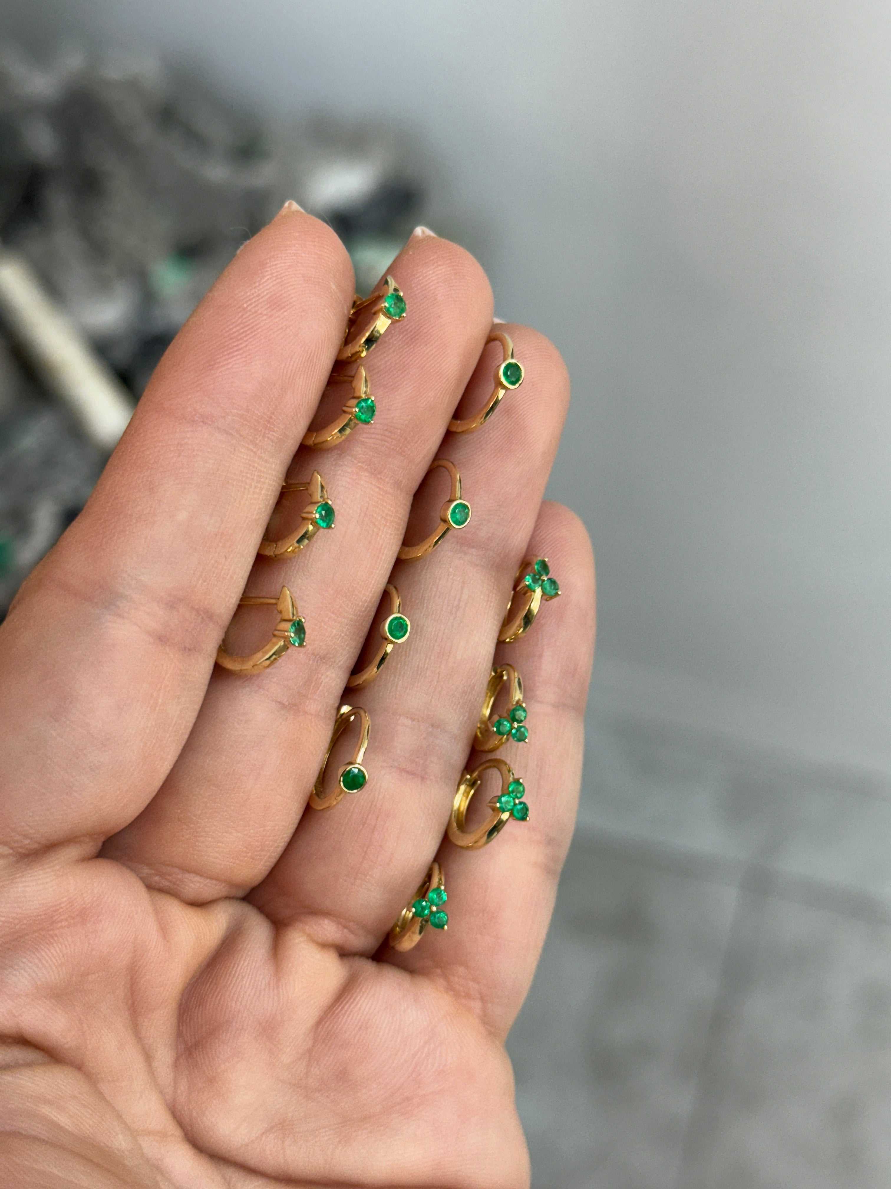 Emerald huggie earring by JR Colombian Emeralds featuring three-prong setting in 14K gold, close-up view of the jewelry.