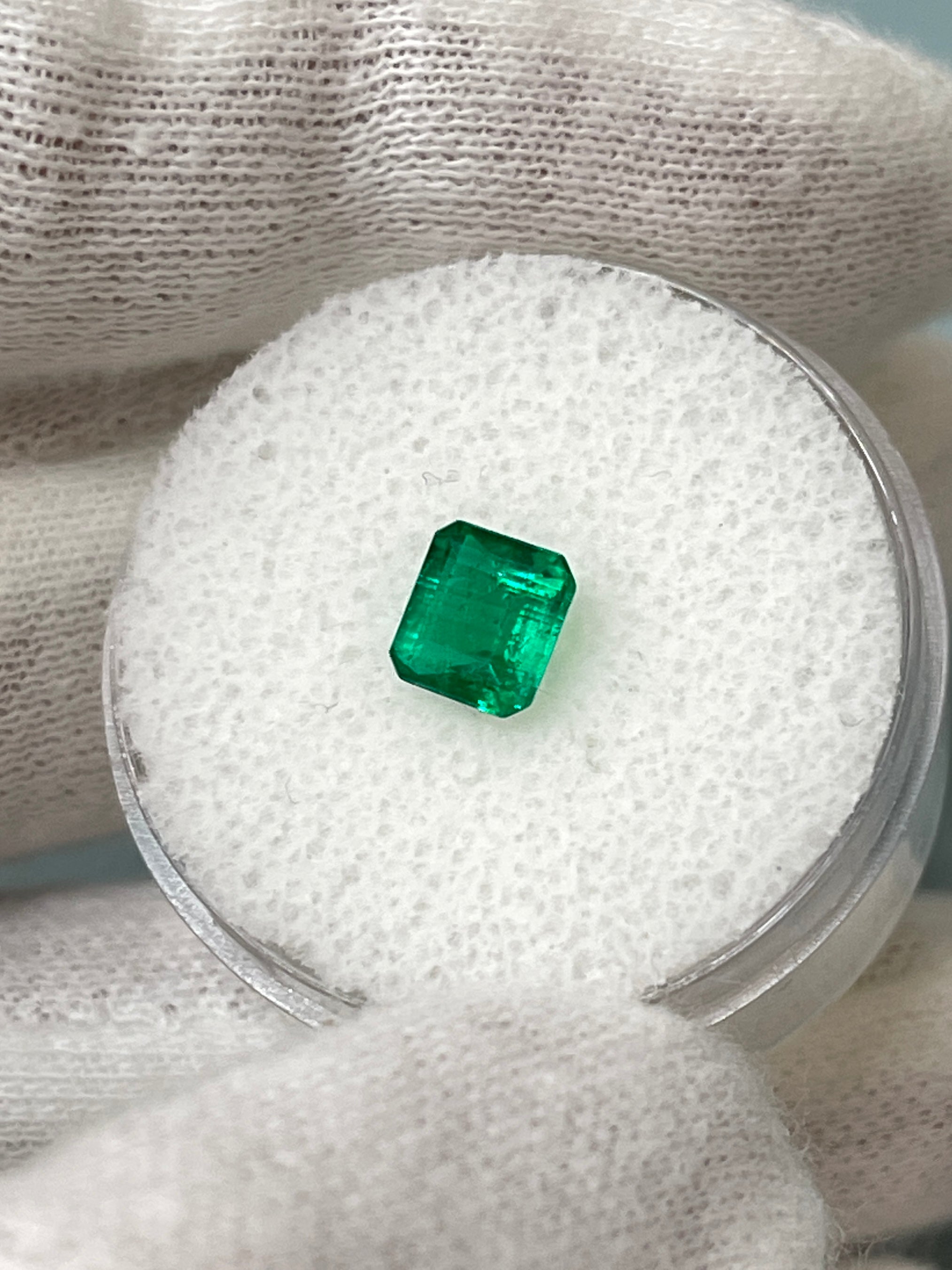 Loose 0.90 carat Colombian emerald in Asscher cut with AAA+ clarity, displayed on a neutral background.