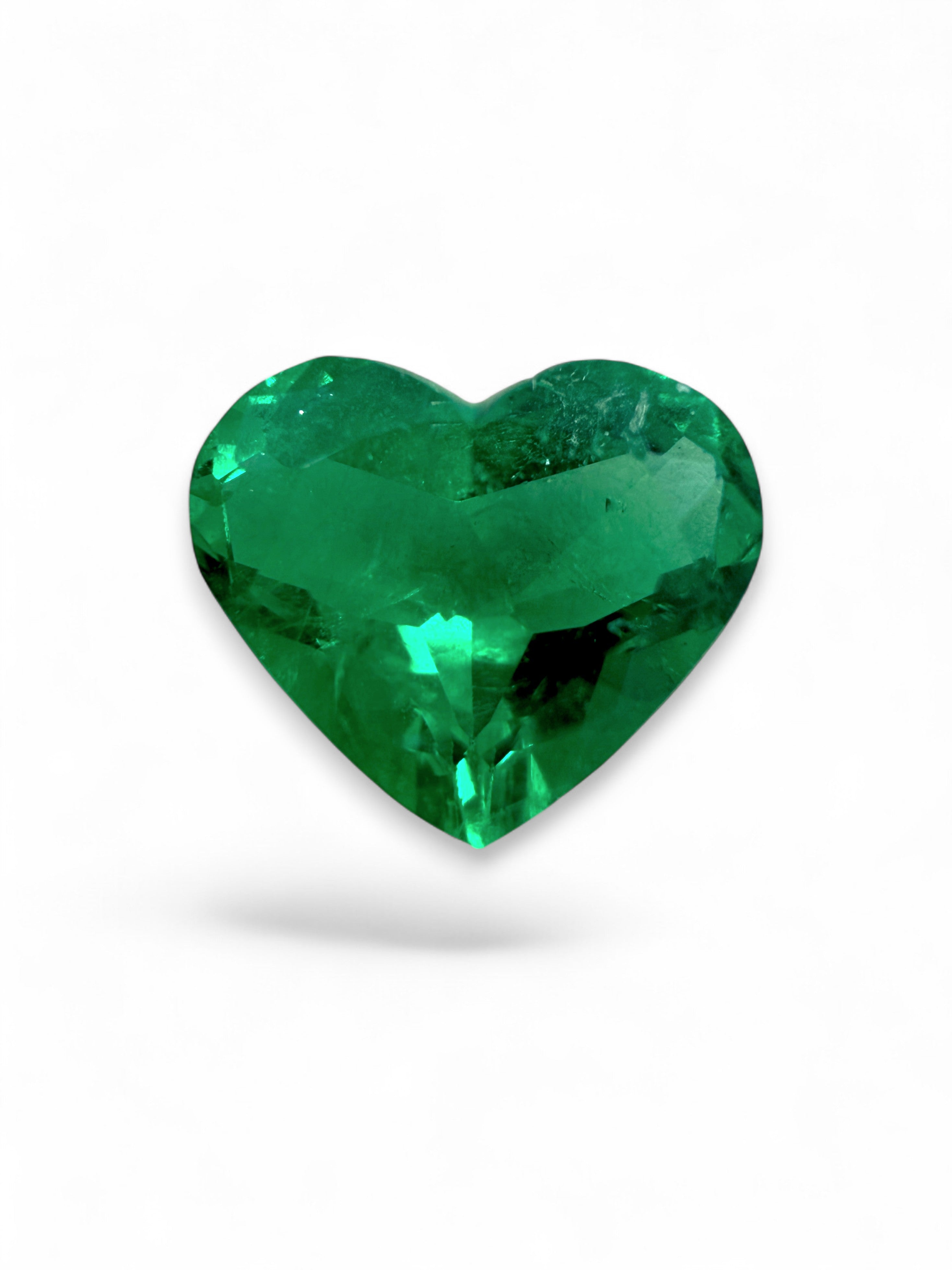 Loose 0.97 carat Muzo green Colombian emerald in heart cut, featuring AAA+ clarity and crystal clean appearance.