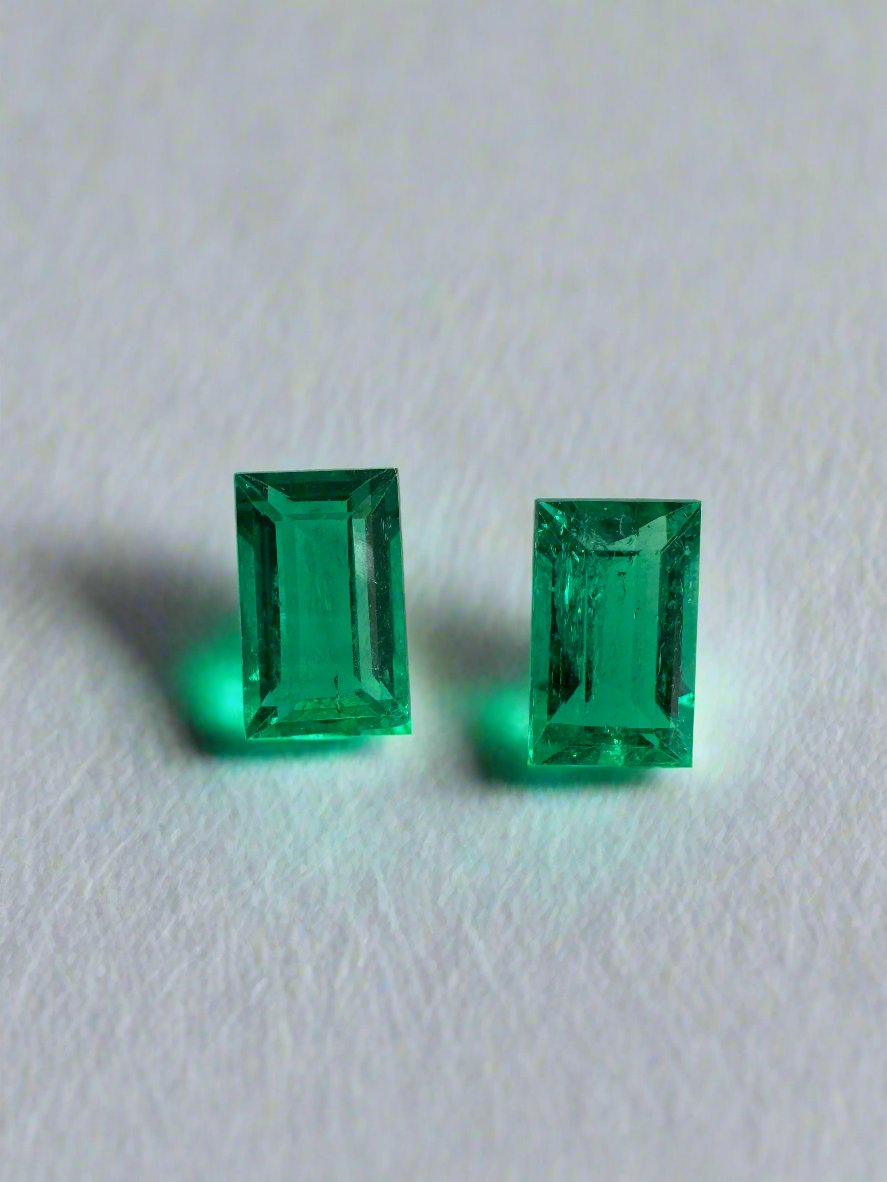 Matching pair of green Colombian emerald baguette cuts, 0.99tcw, showcasing their vibrant color and clarity.