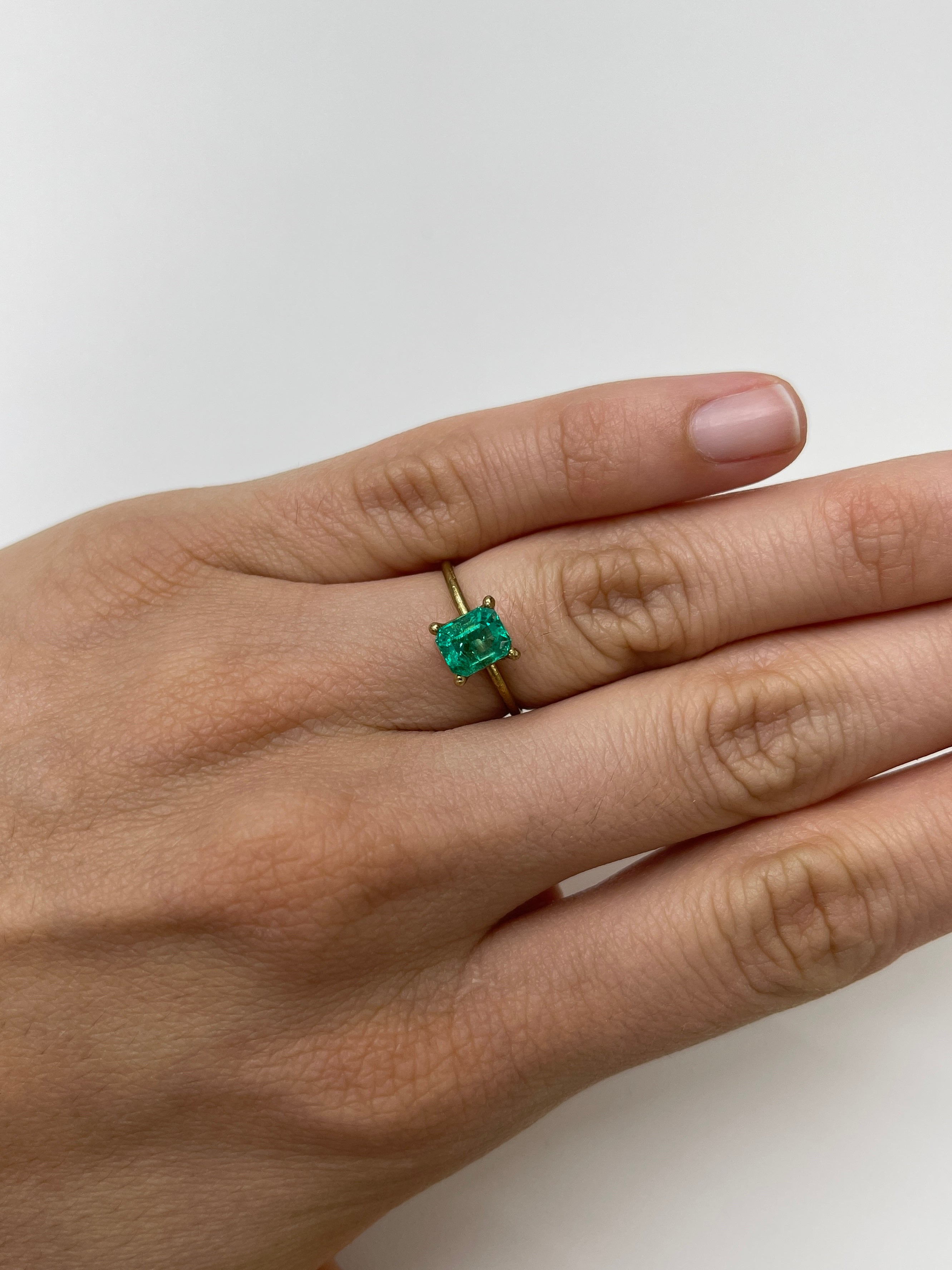 1.22 Carat bluish green natural Colombian emerald loose gemstone in emerald cut, displayed on a white background.
