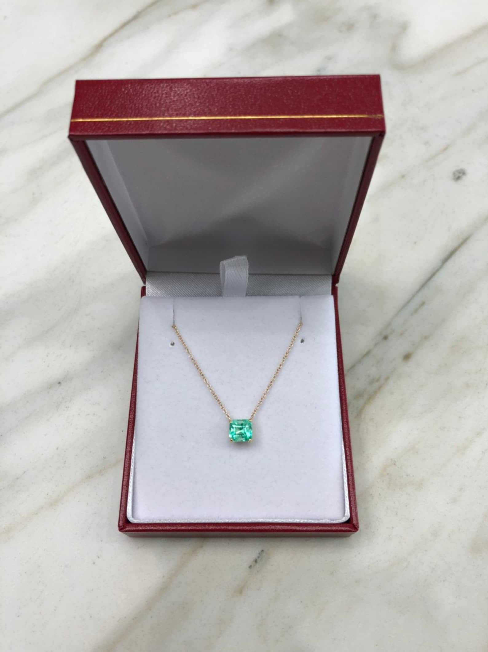 Rich green Colombian emerald necklace featuring a 1.30 carat solitaire emerald cut gemstone set in 14K gold.