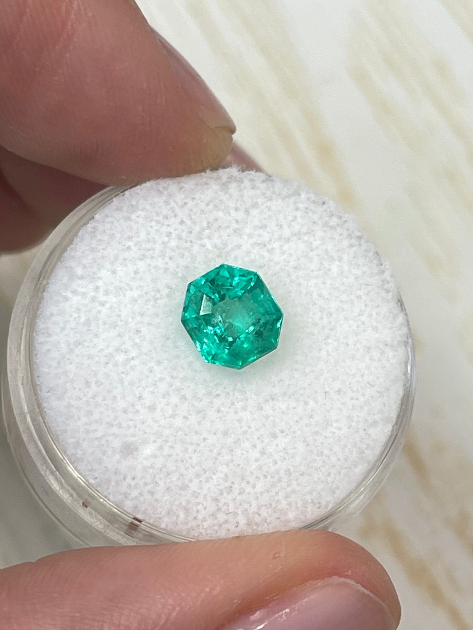 Bluish green 1.50 carat octagon cut Colombian emerald, natural and unset, displayed with vibrant color and clarity.