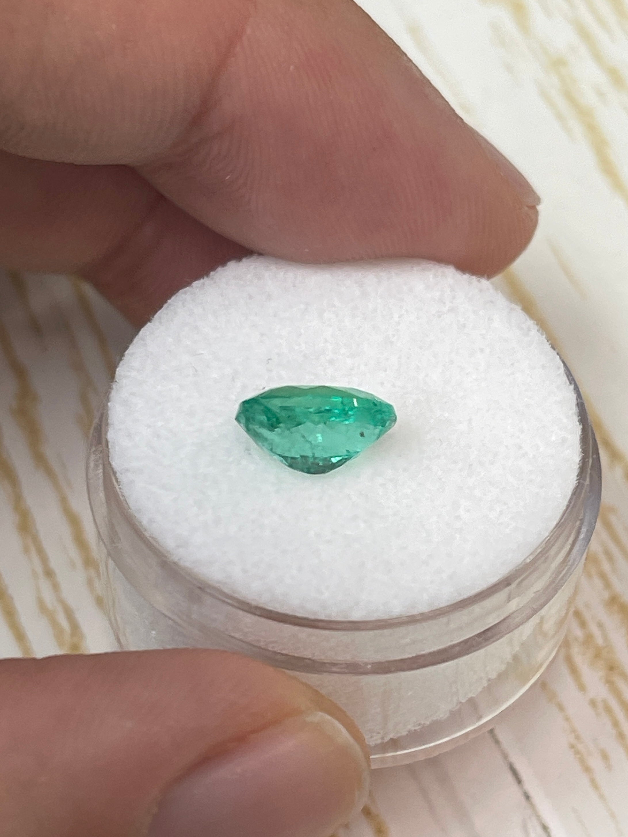 Oval-cut 1.64 carat green natural Colombian emerald loose gemstone from JR Colombian Emeralds, shown on a neutral background.