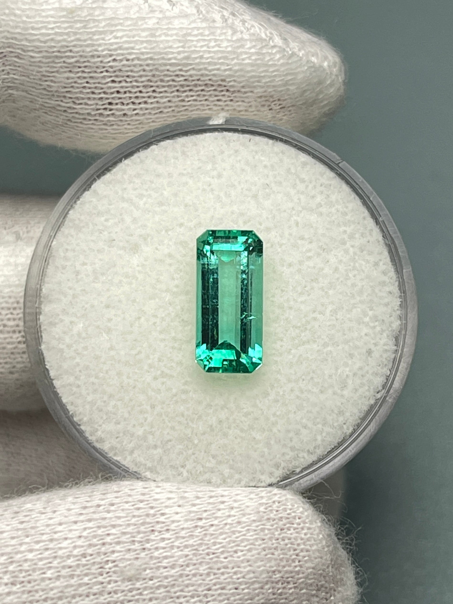 Natural 1.65 carat Colombian emerald loose gemstone with elongated emerald cut, crystalline clarity, vibrant green color.