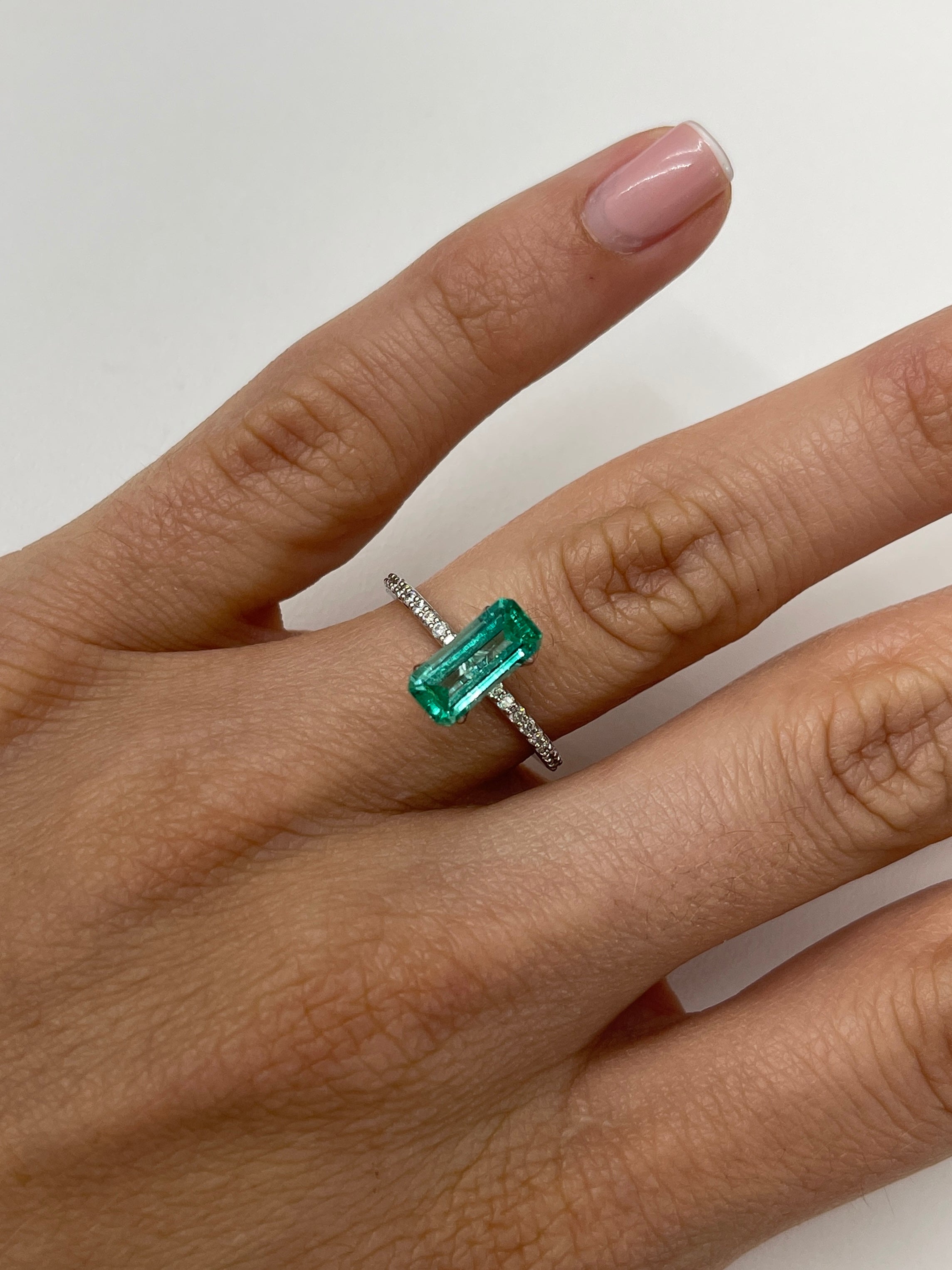 Natural 1.65 carat Colombian emerald loose gemstone with an elongated emerald cut, showcasing crystalline clarity and vibrant green color.