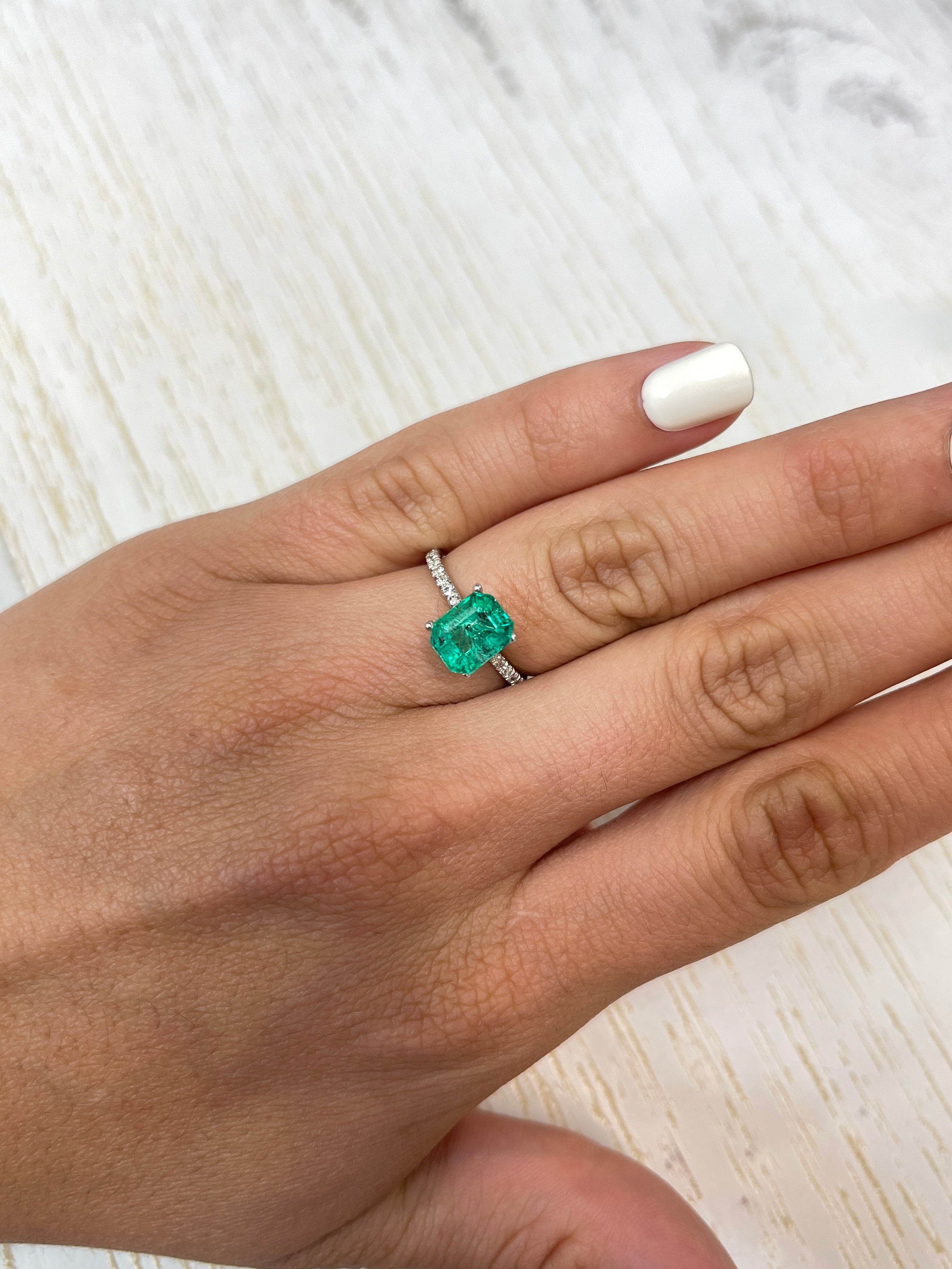Freckled bluish-green 2.12 carat Colombian emerald loose gemstone in emerald cut, displayed by JR Colombian Emeralds.