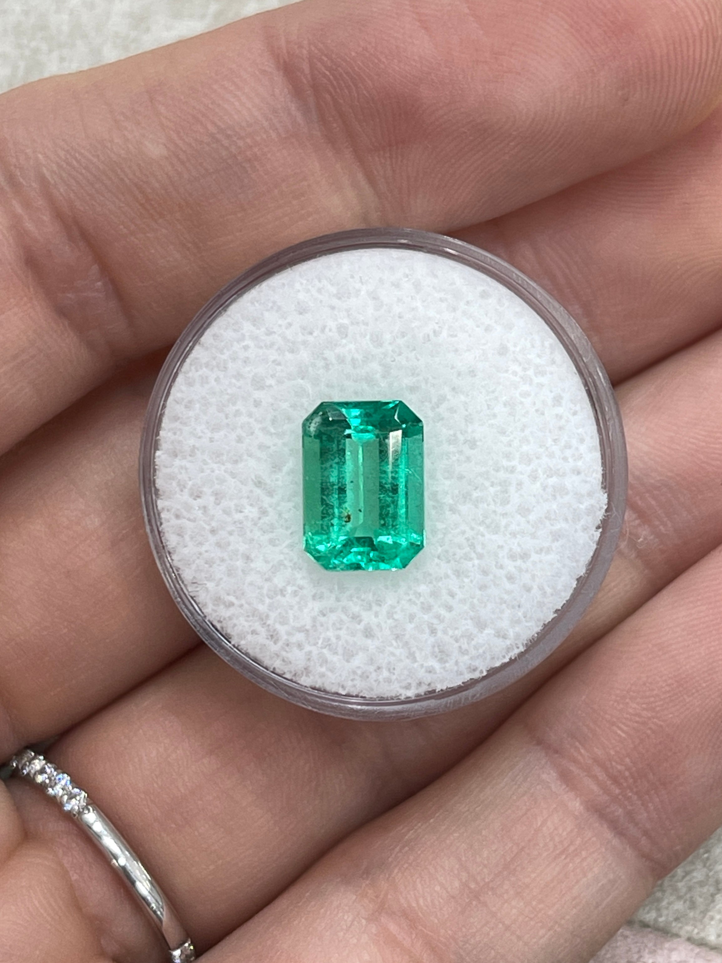 Freckled 2.31 Carat medium green Colombian emerald cut emerald from JR Colombian Emeralds, showcasing a vibrant green color.