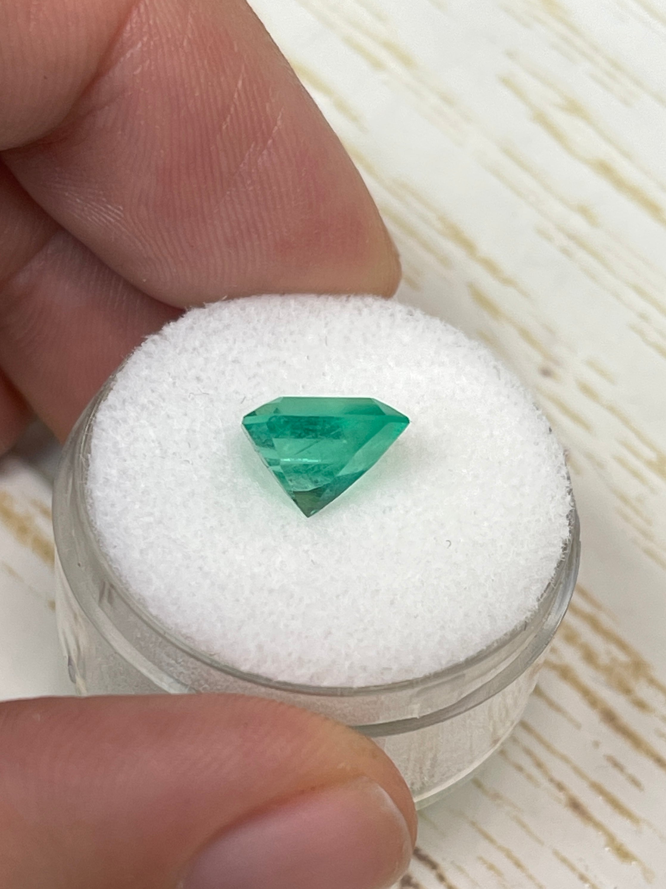 Natural 2.44 carat spring green Colombian emerald gemstone in an emerald cut, displayed against a neutral background.