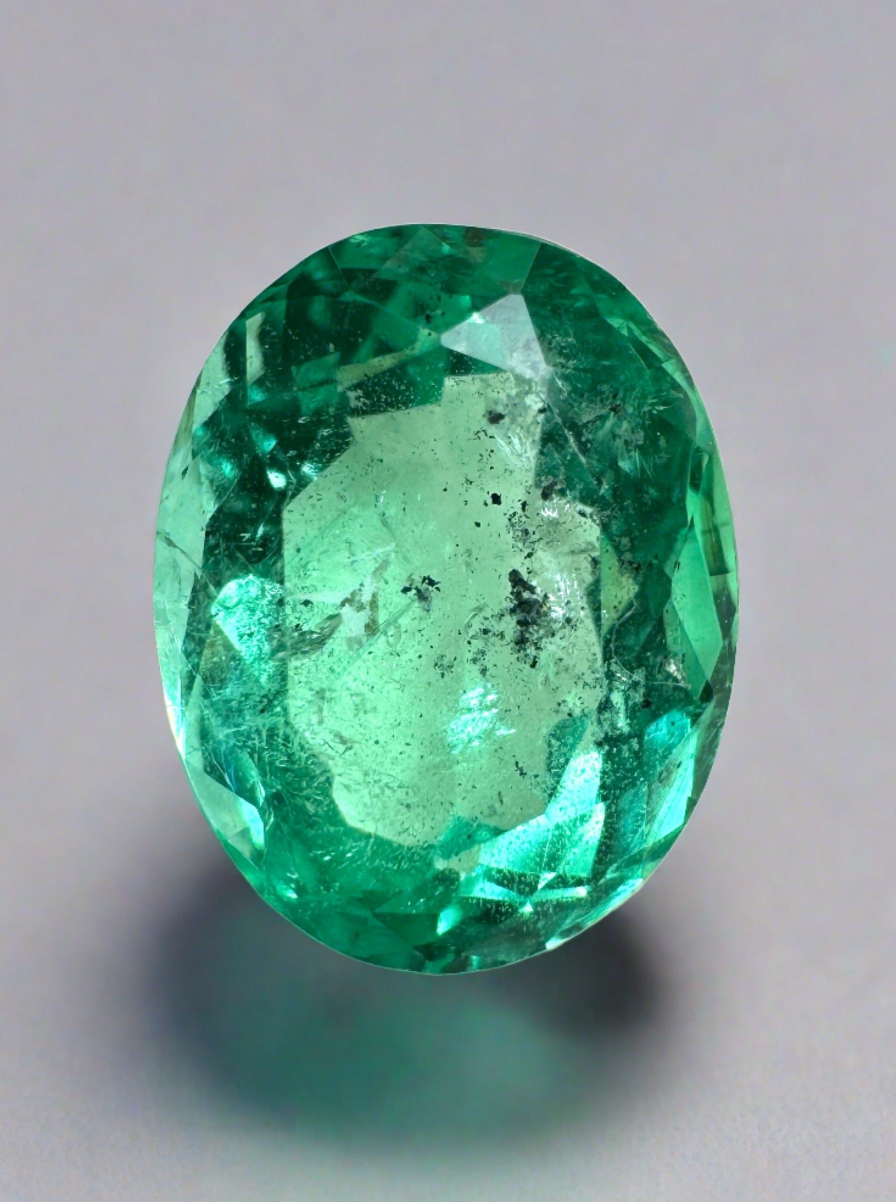 Vibrant 2.83 carat oval cut Colombian emerald with natural freckles, loose green gemstone from JR Colombian Emeralds.