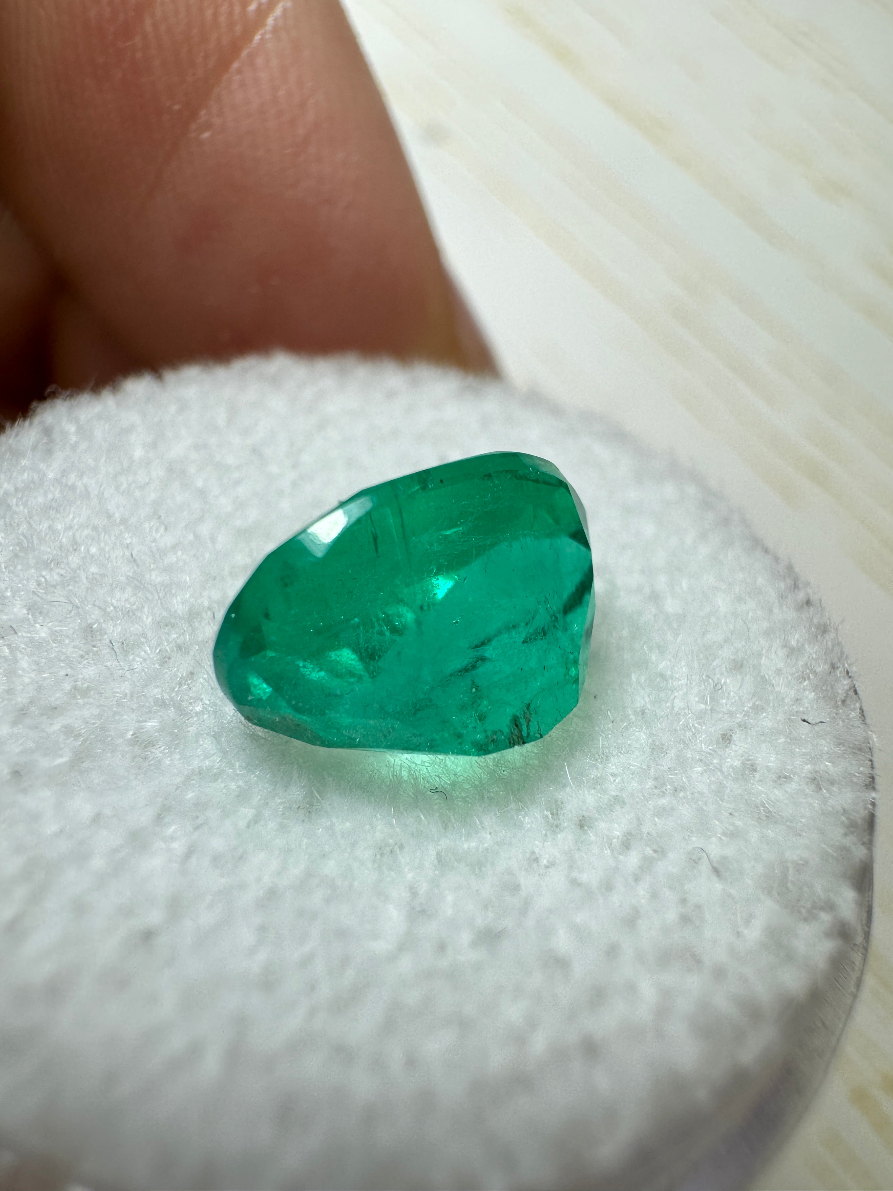 Elongated 2.95 carat semi-transparent green Colombian emerald with oval cut, showcasing vibrant color and clarity.