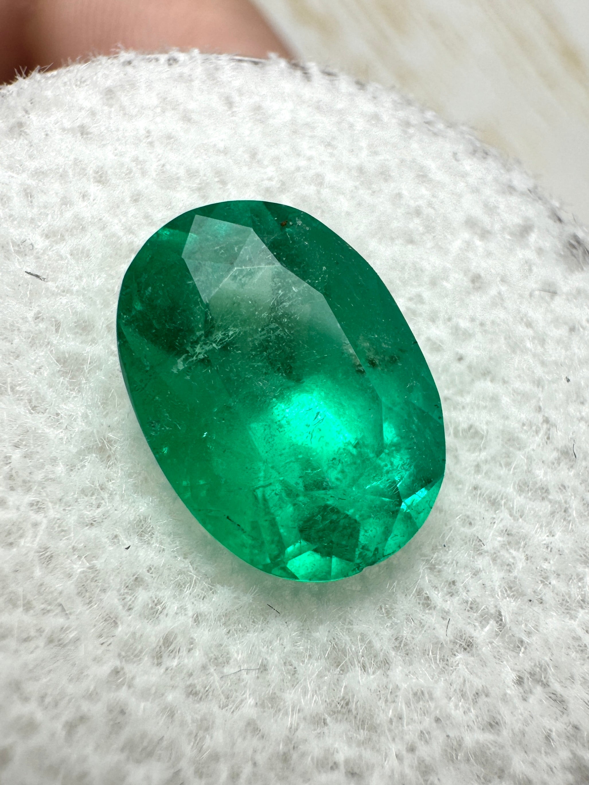 Elongated 2.95 carat semi-transparent green Colombian emerald loose gemstone in oval cut, displayed against a neutral background.