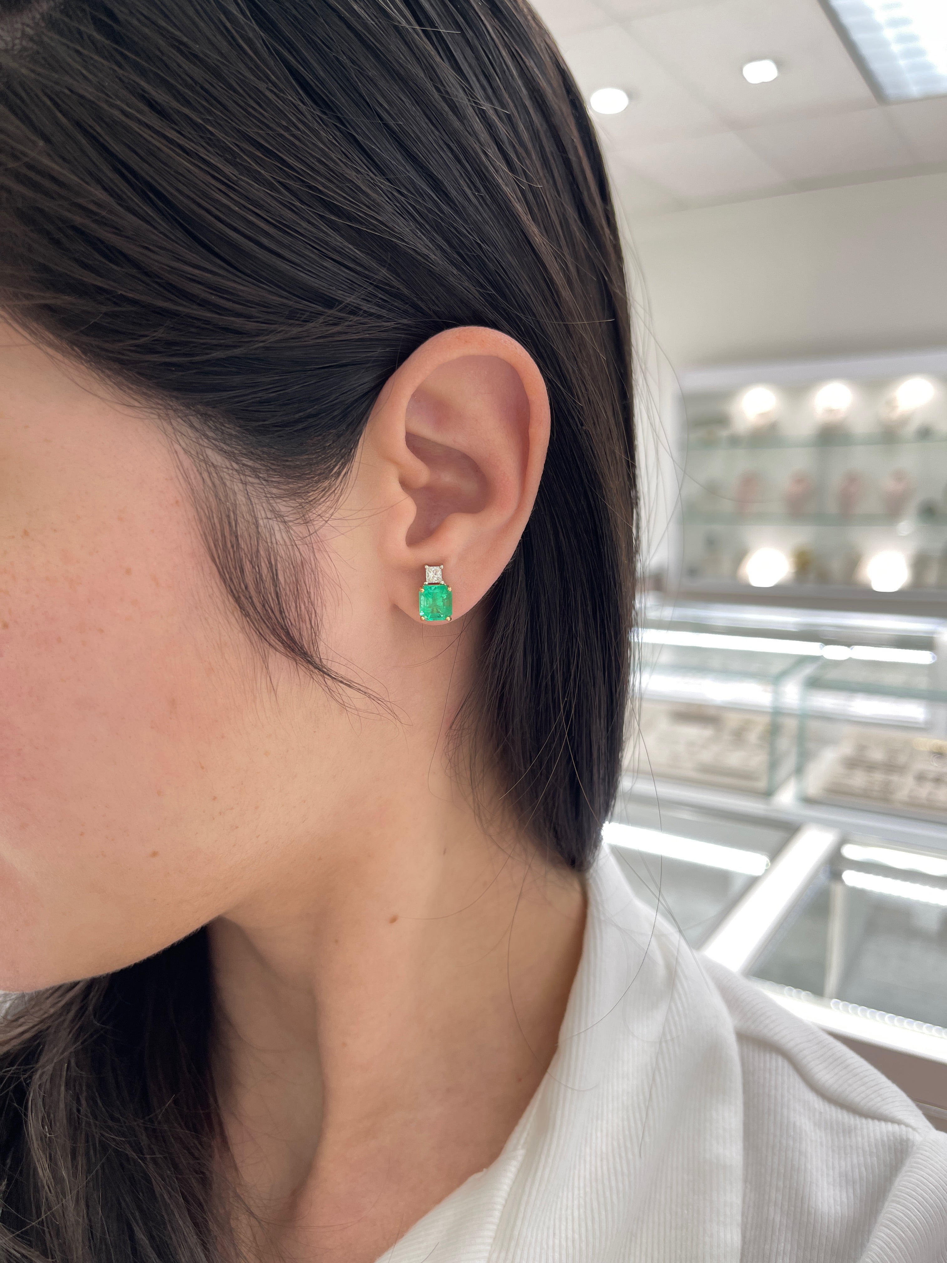 Colombian emerald and princess cut diamond earrings in 18K two-tone gold, featuring vibrant green emeralds and sparkling diamonds.