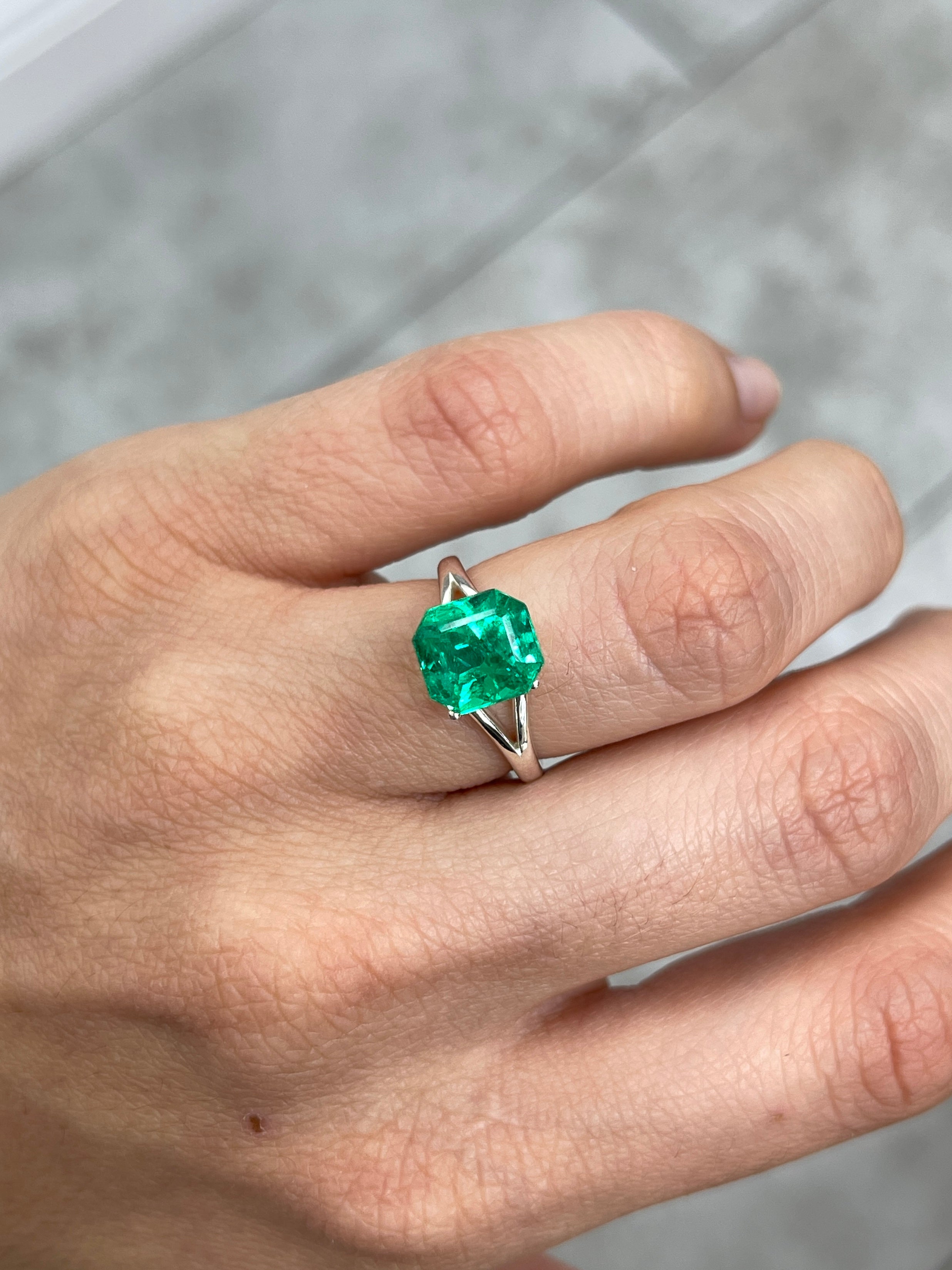 3.26 Carat vivid yellowish green Colombian emerald in an emerald cut, showcased against a neutral background.