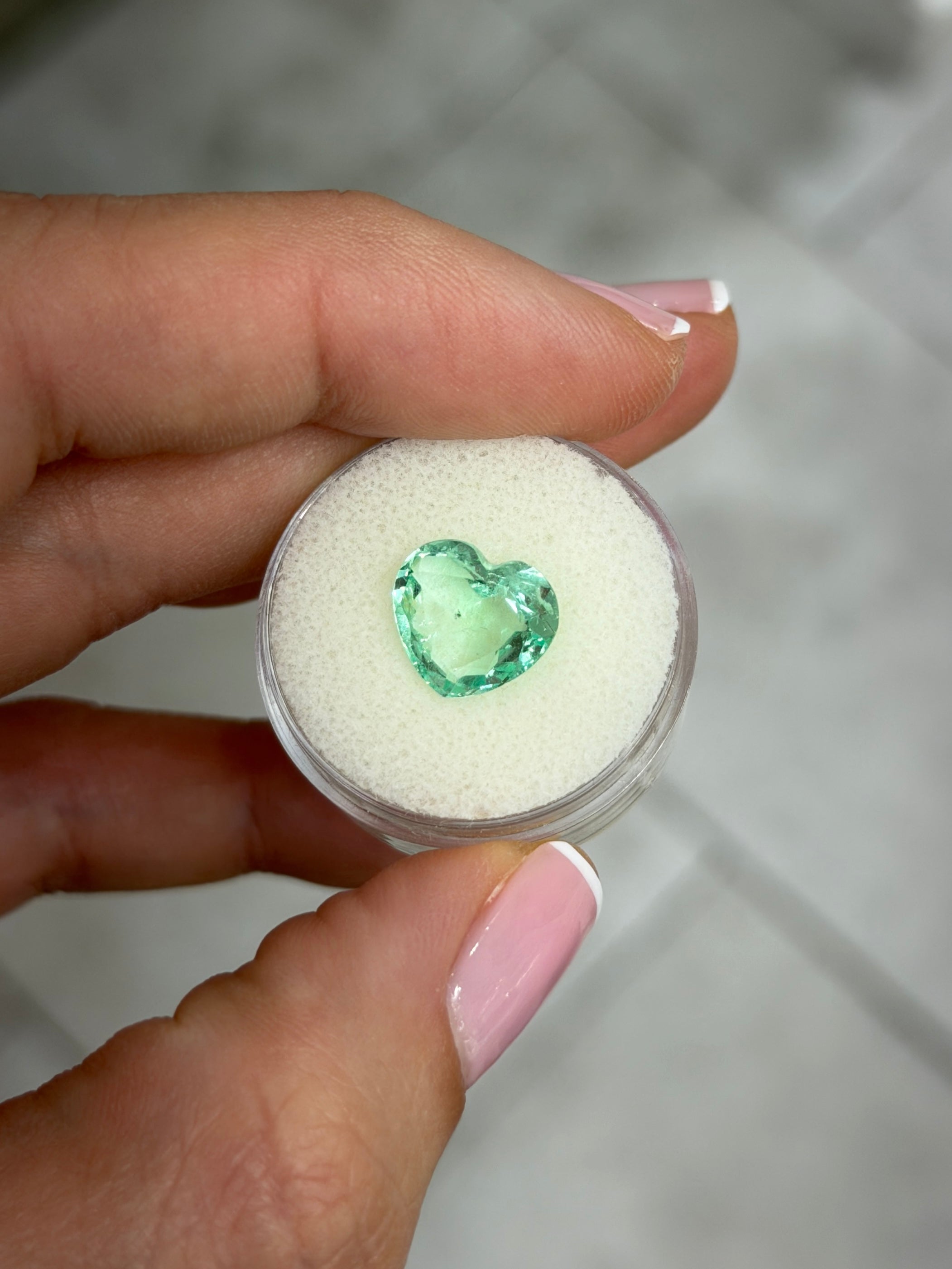 Light bluish green Colombian emerald in 10x11 portrait cut with freckles, heart shape, loose gemstone by JR Colombian Emeralds.