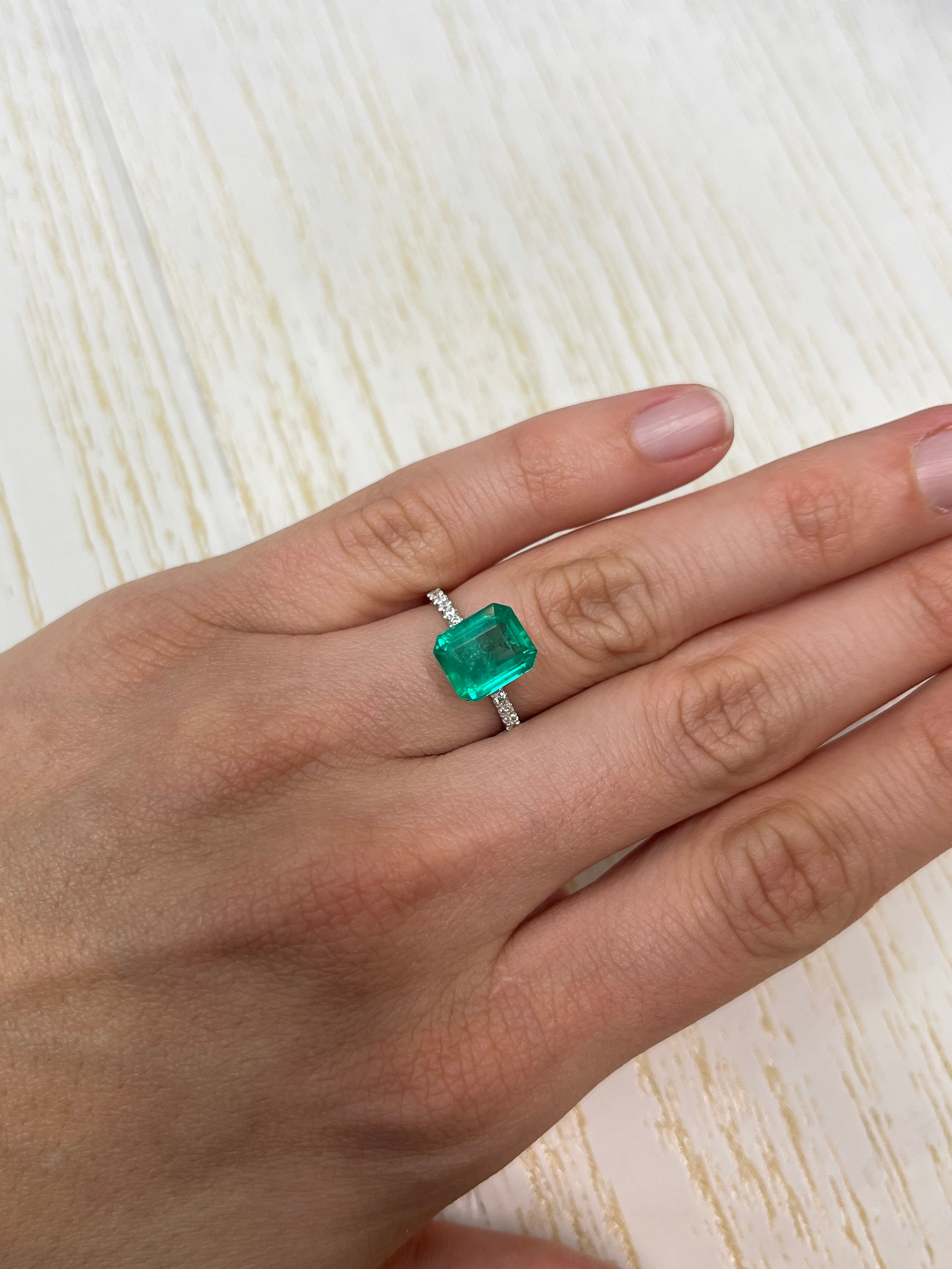 3.53 carat medium bluish green Colombian emerald loose gemstone in an emerald cut, displayed against a neutral background.
