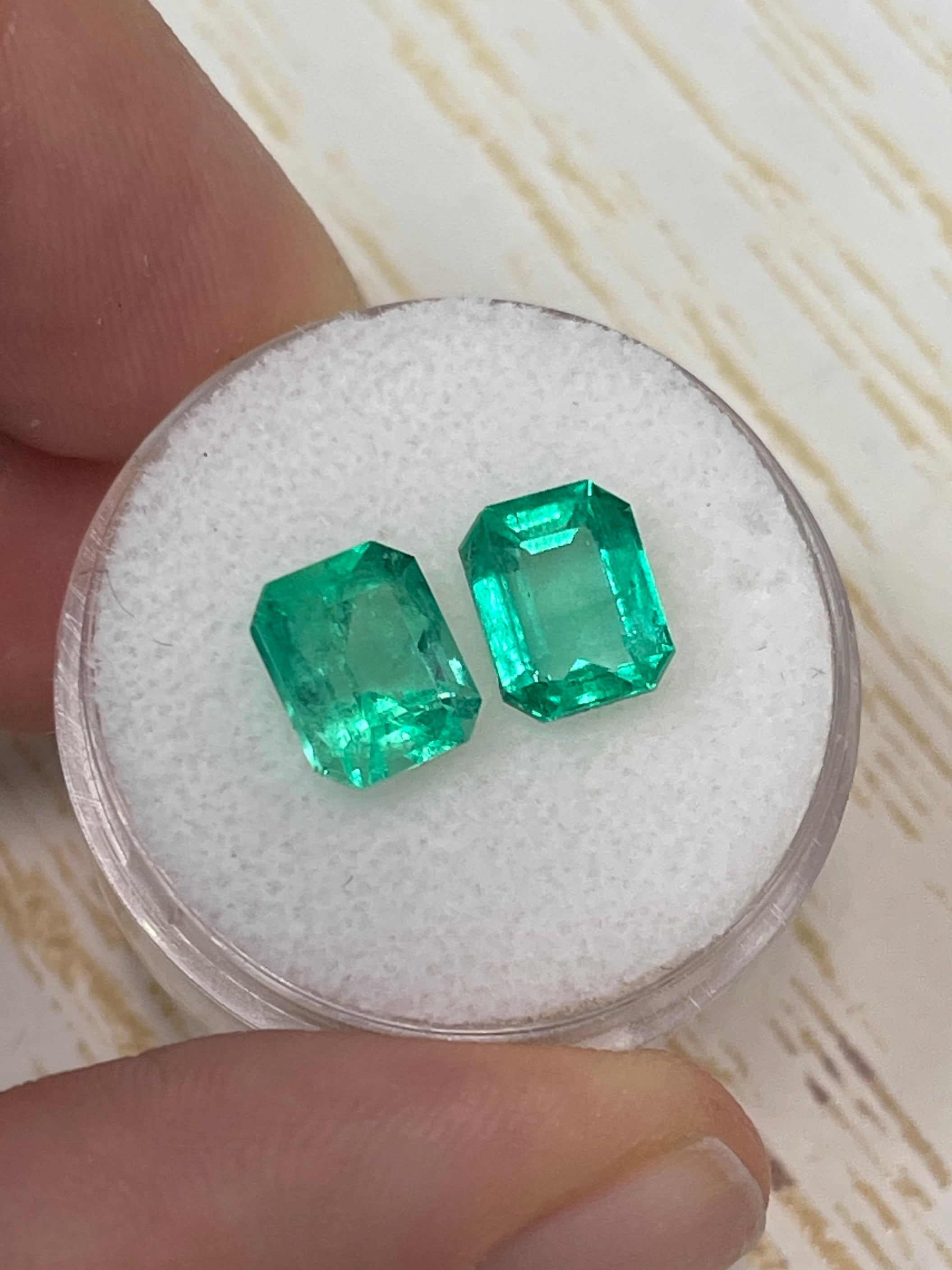 Pair of 3.73 carat Colombian emeralds in emerald cut, matching loose green gems with vibrant color and clarity.