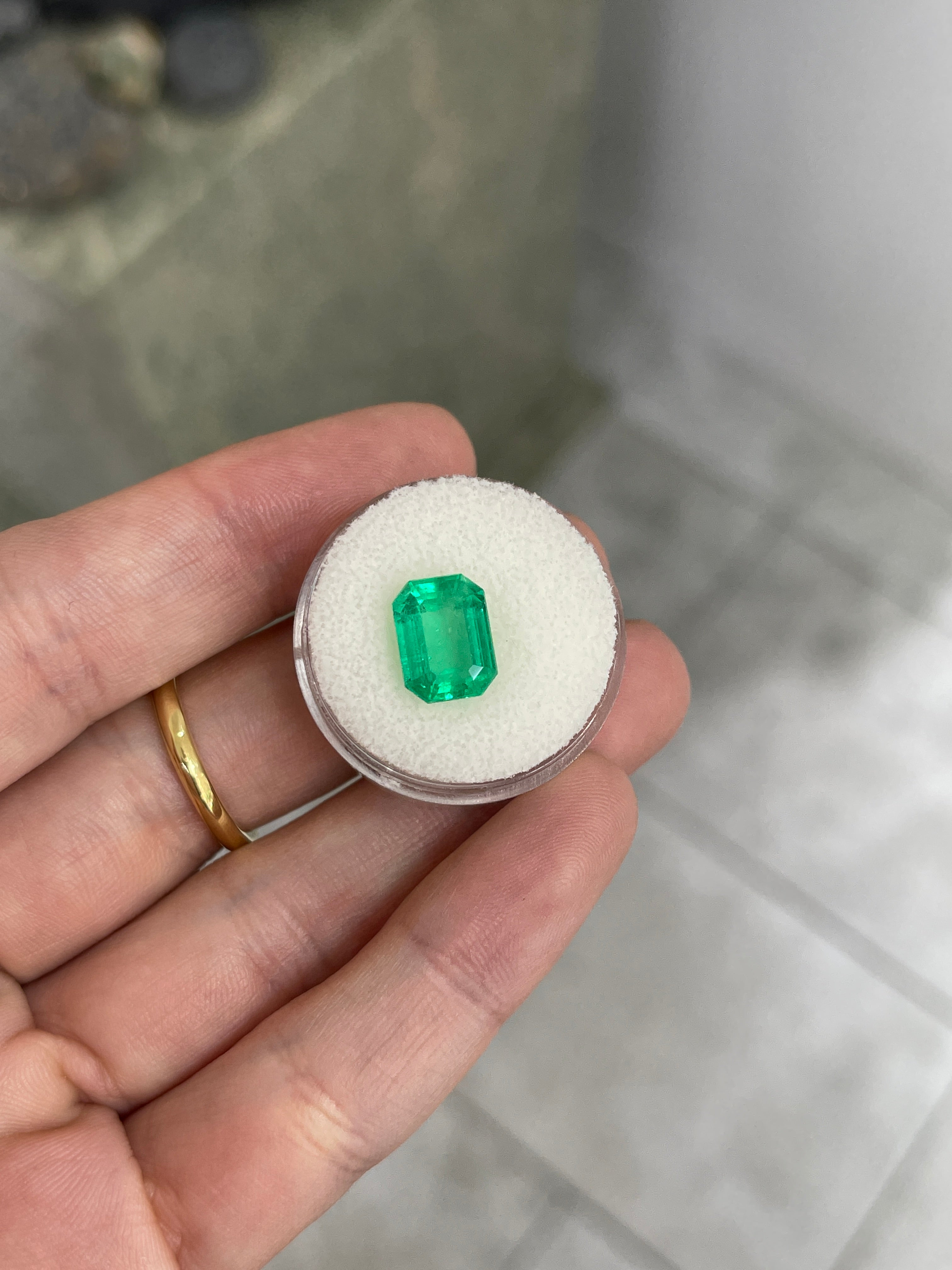 3.88 carat glowing green Colombian emerald loose gemstone in an emerald cut, showing vibrant natural coloration and clarity.