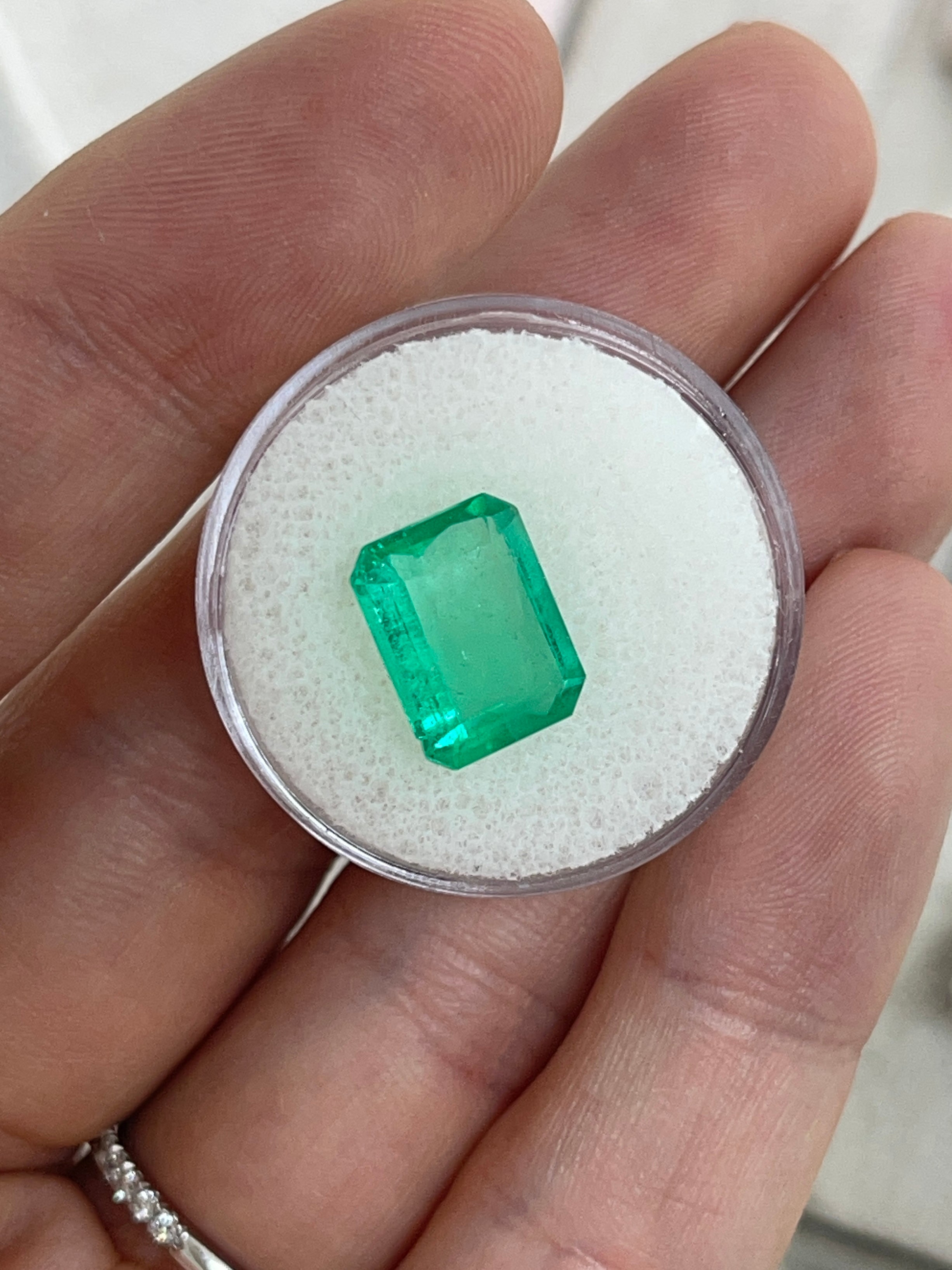 Natural 4.12 carat Colombian emerald loose gemstone in 12x9 portrait cut, showcasing vibrant green color and emerald cut facets.