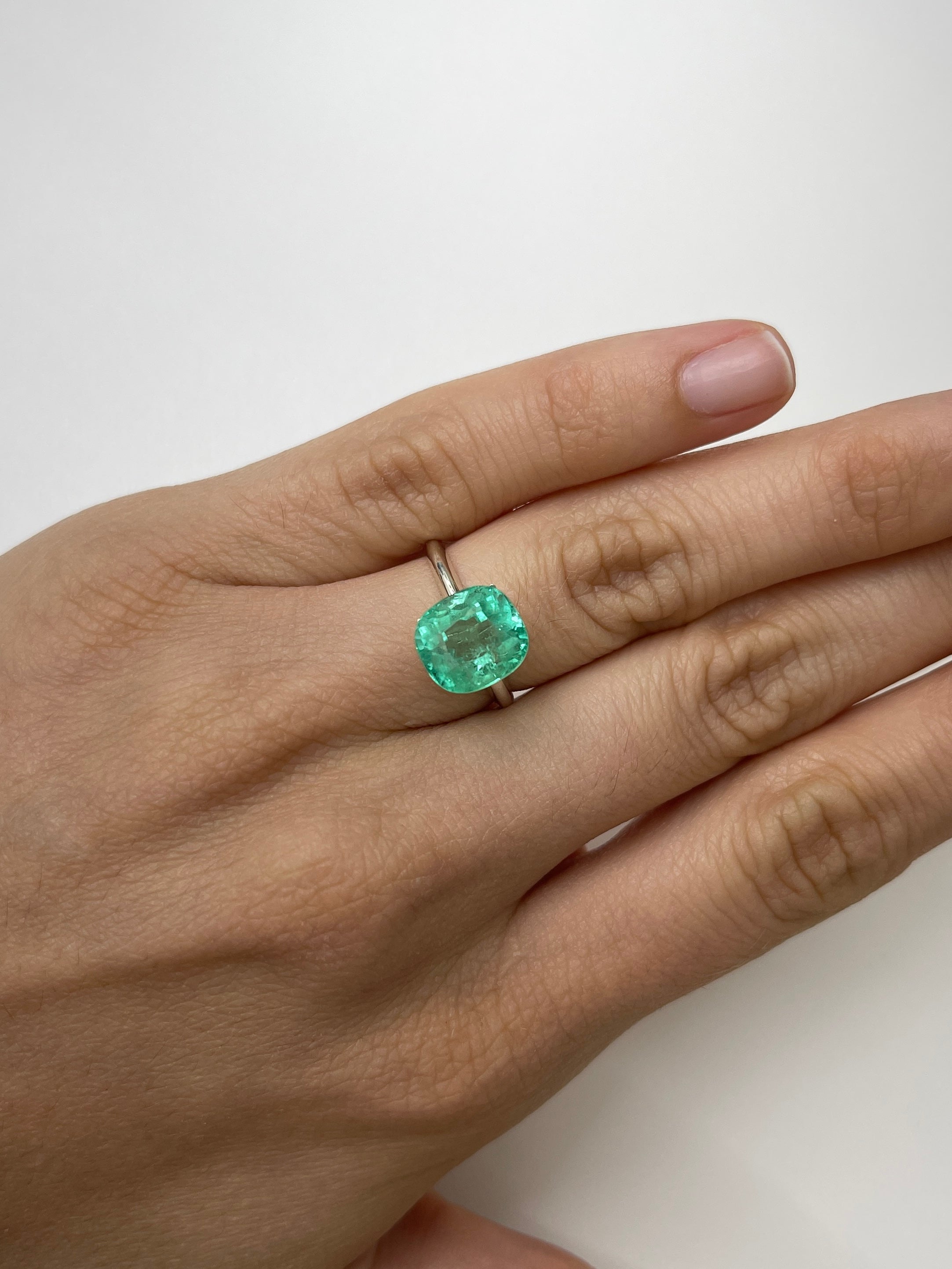 Loose 4.71 carat light green Colombian emerald, cushion cut, showcasing its gemmy clarity and rich color.