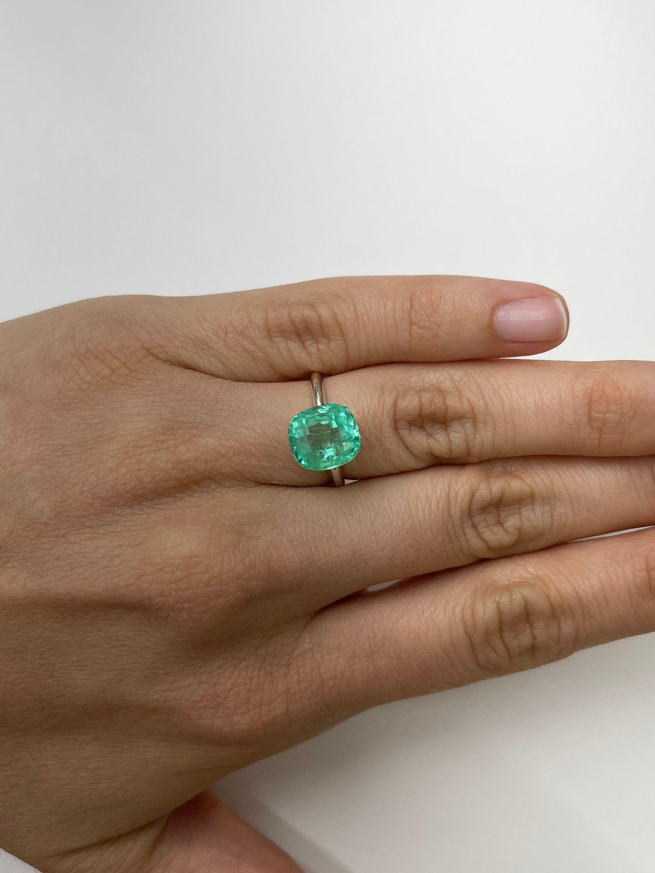 Light green cushion cut Colombian emerald, 4.71 carats, displaying gemmy clarity and natural beauty.